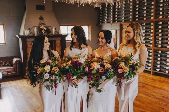 A bride and her bridesmaids are standing in a room holding bouquets of flowers.