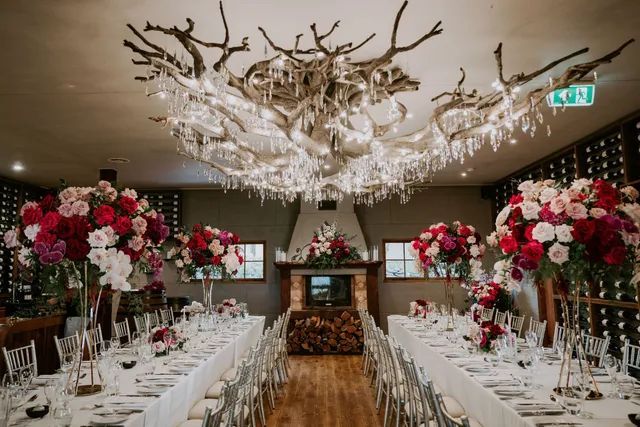 A long table set for a wedding reception with a chandelier hanging from the ceiling.