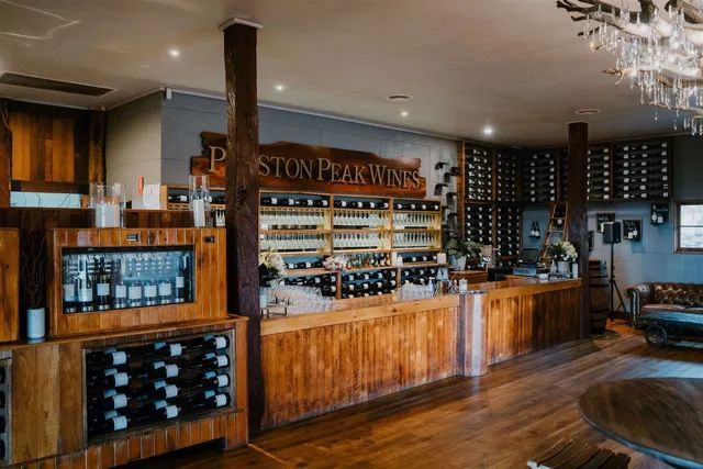 A large room filled with wooden tables and shelves filled with wine bottles.