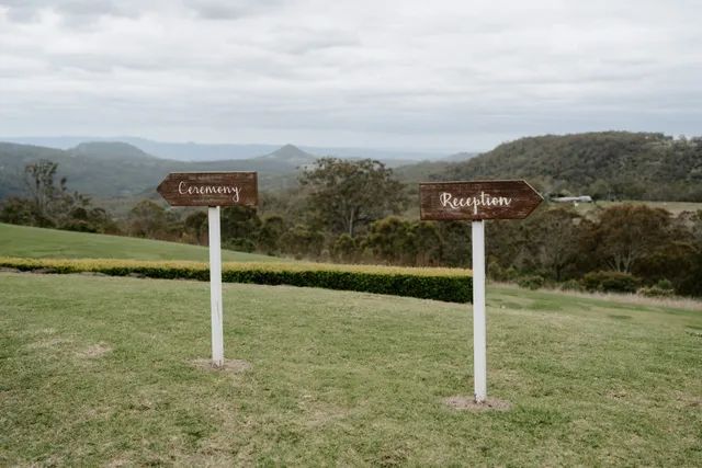 Two wooden signs in a grassy field pointing in opposite directions.