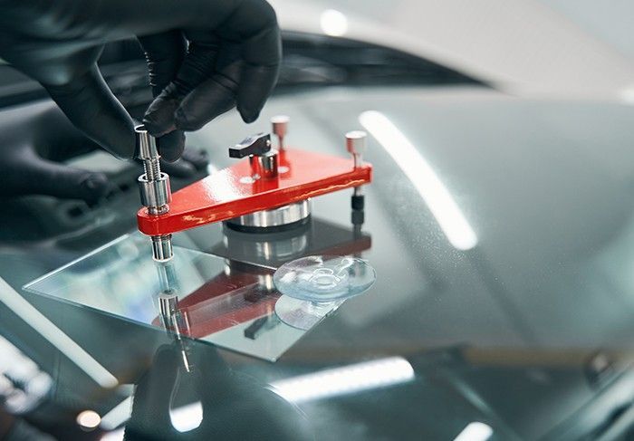 A person is repairing a cracked windshield on a car.