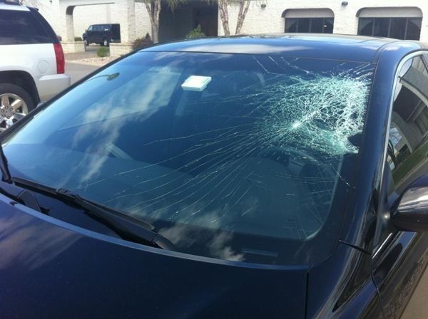 A car with a broken windshield is parked in a driveway
