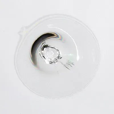 A close up of a glass with a hole in it on a white surface.