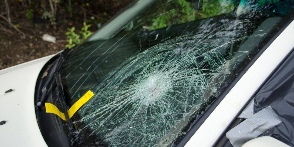 A close up of a broken windshield on a white car.