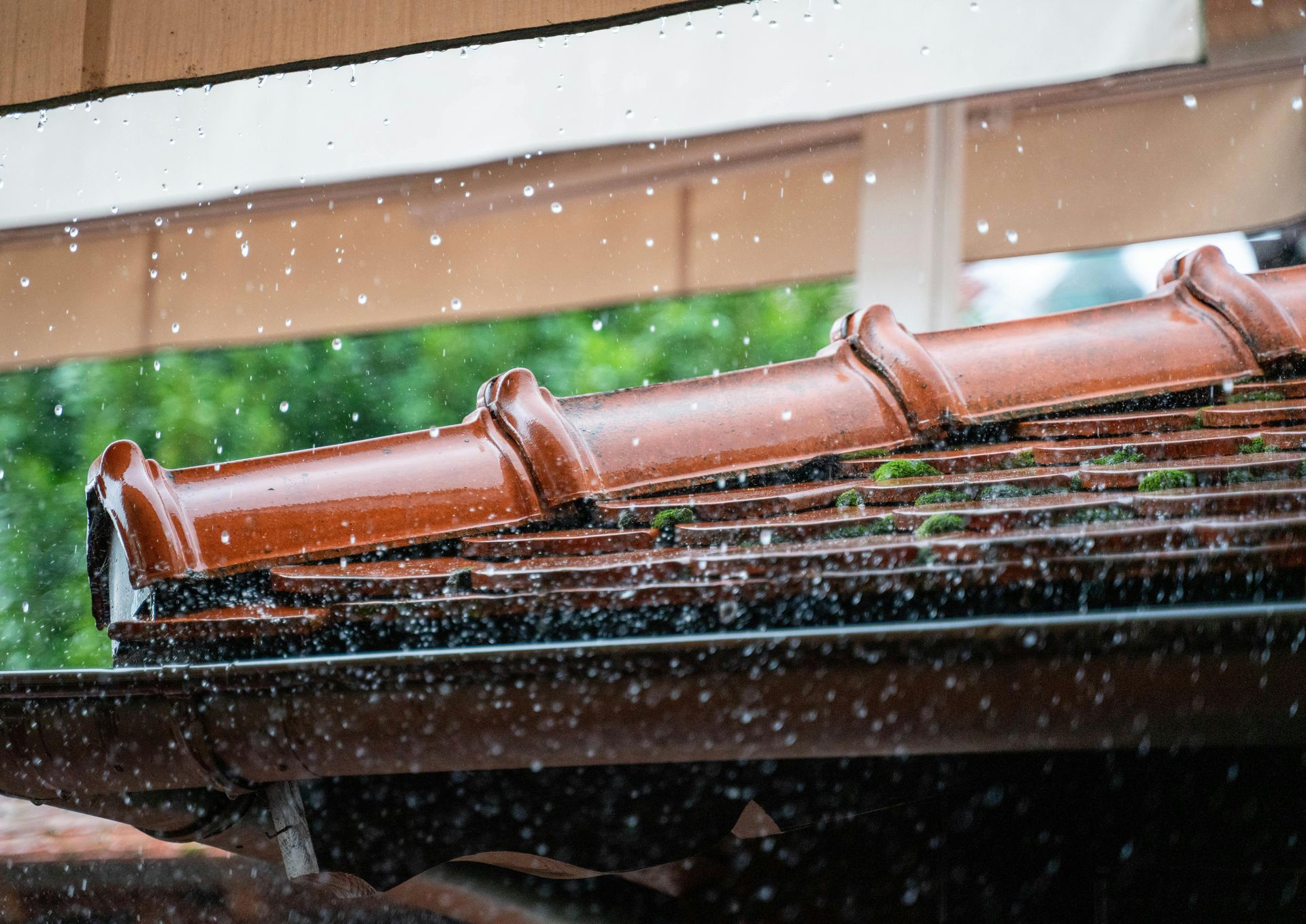 A close up of a roof with gutter guard, rain falling on it.