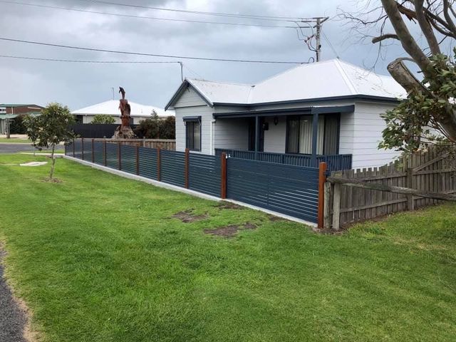 A white house with a blue fence in front of it.