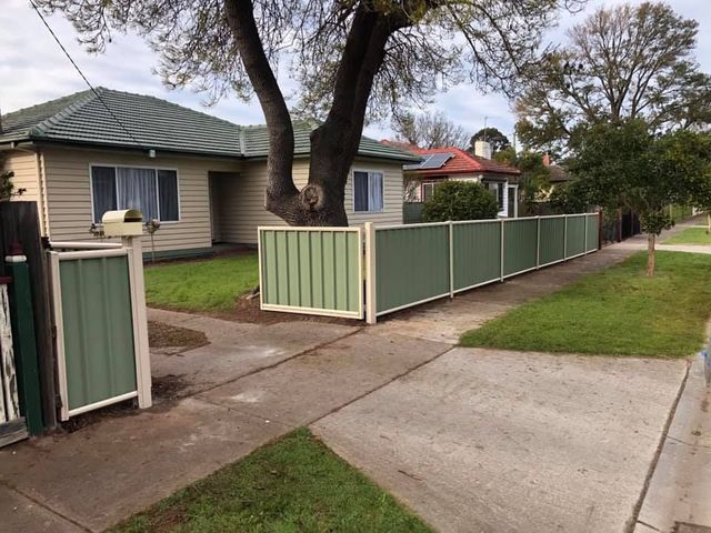 A house with a green fence in front of it