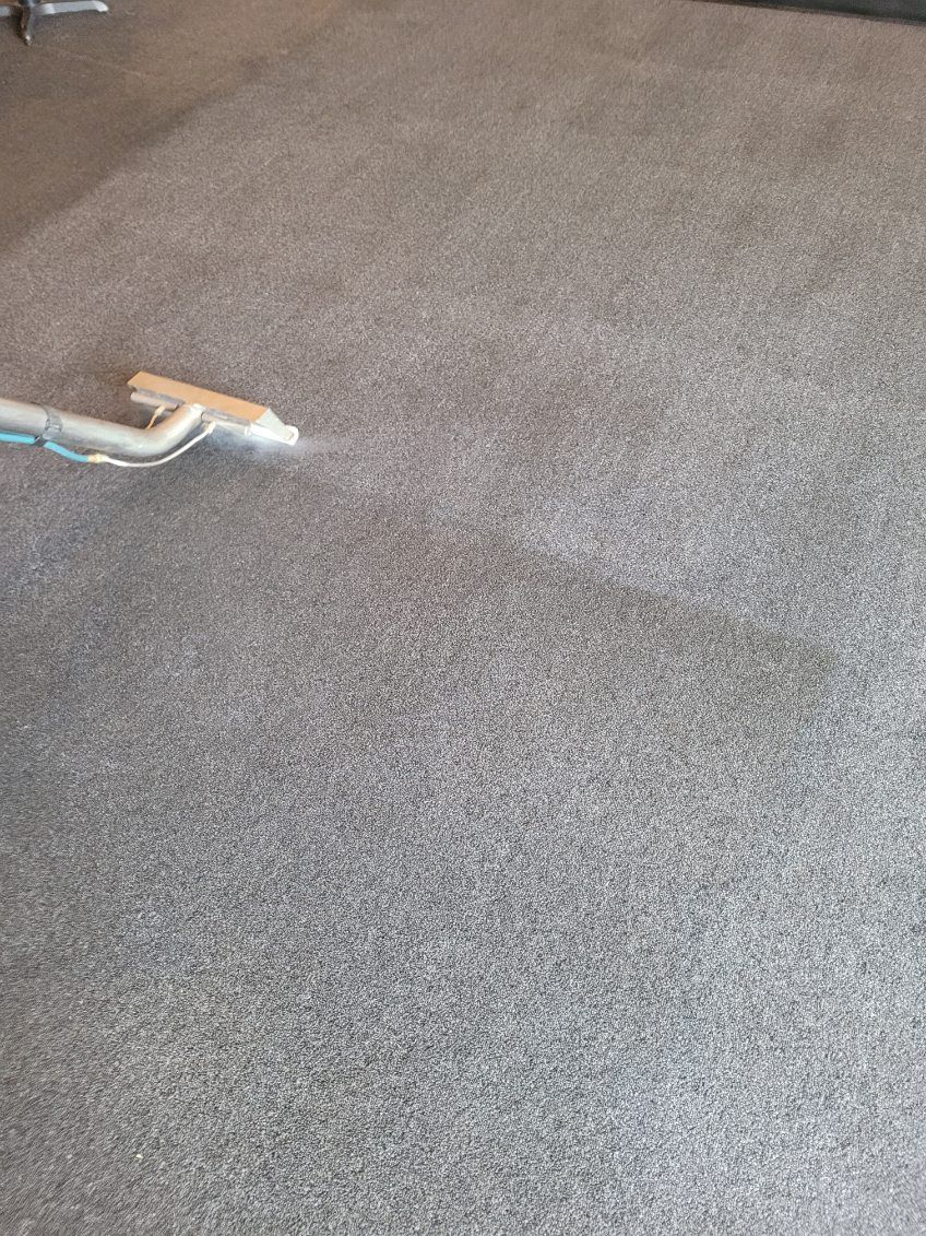 A person is cleaning a couch with a vacuum cleaner.