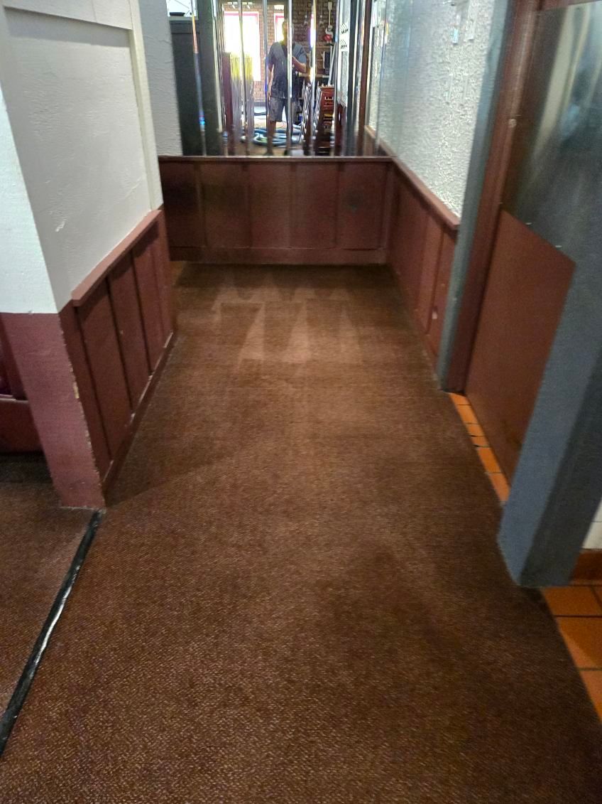 A long hallway with a brown carpet and wood paneling.