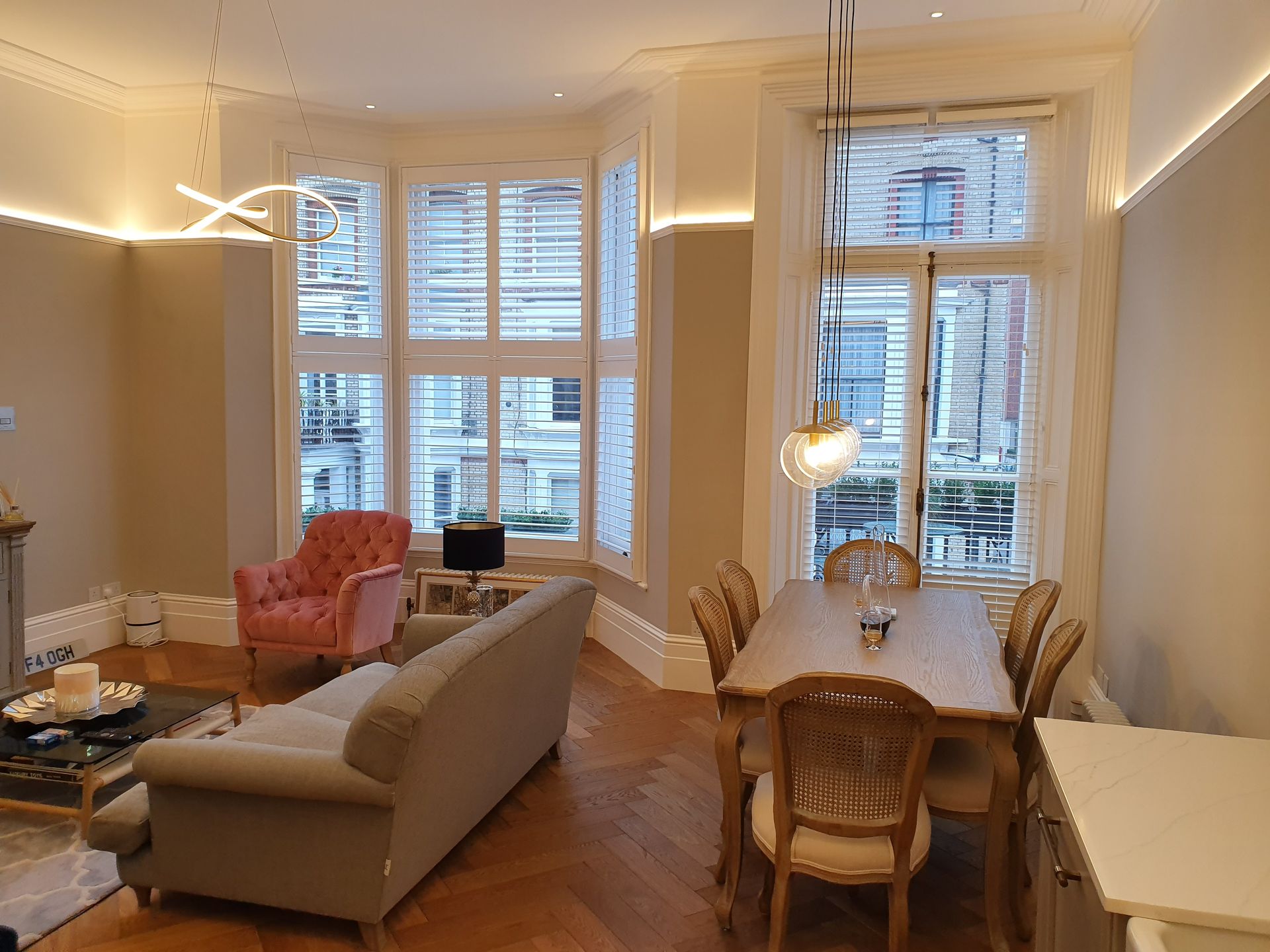Elegant living and dining room interior with wooden flooring and window shutters in London property