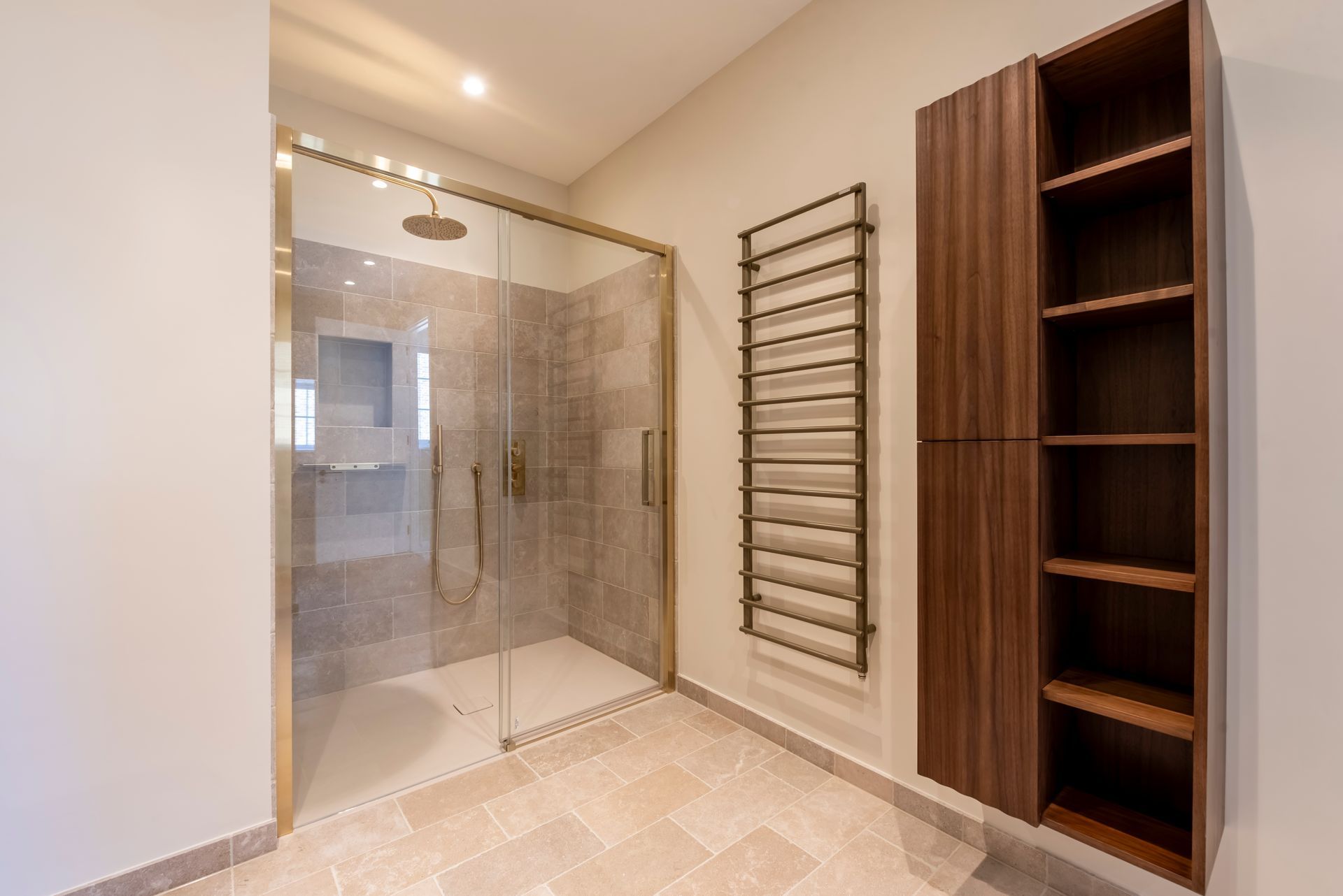Modern bathroom with glass shower, wall towel rack, and dark wood shelving unit.