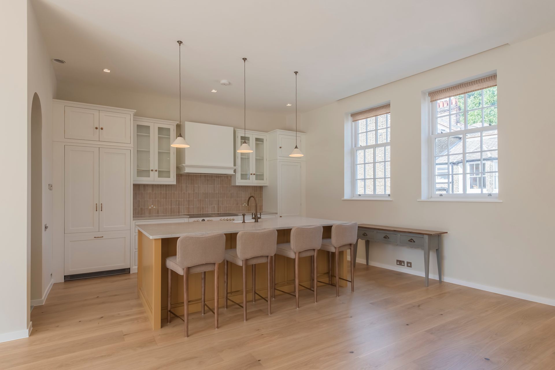 Bright modern kitchen with island, pendant lights, white cabinets, and large windows