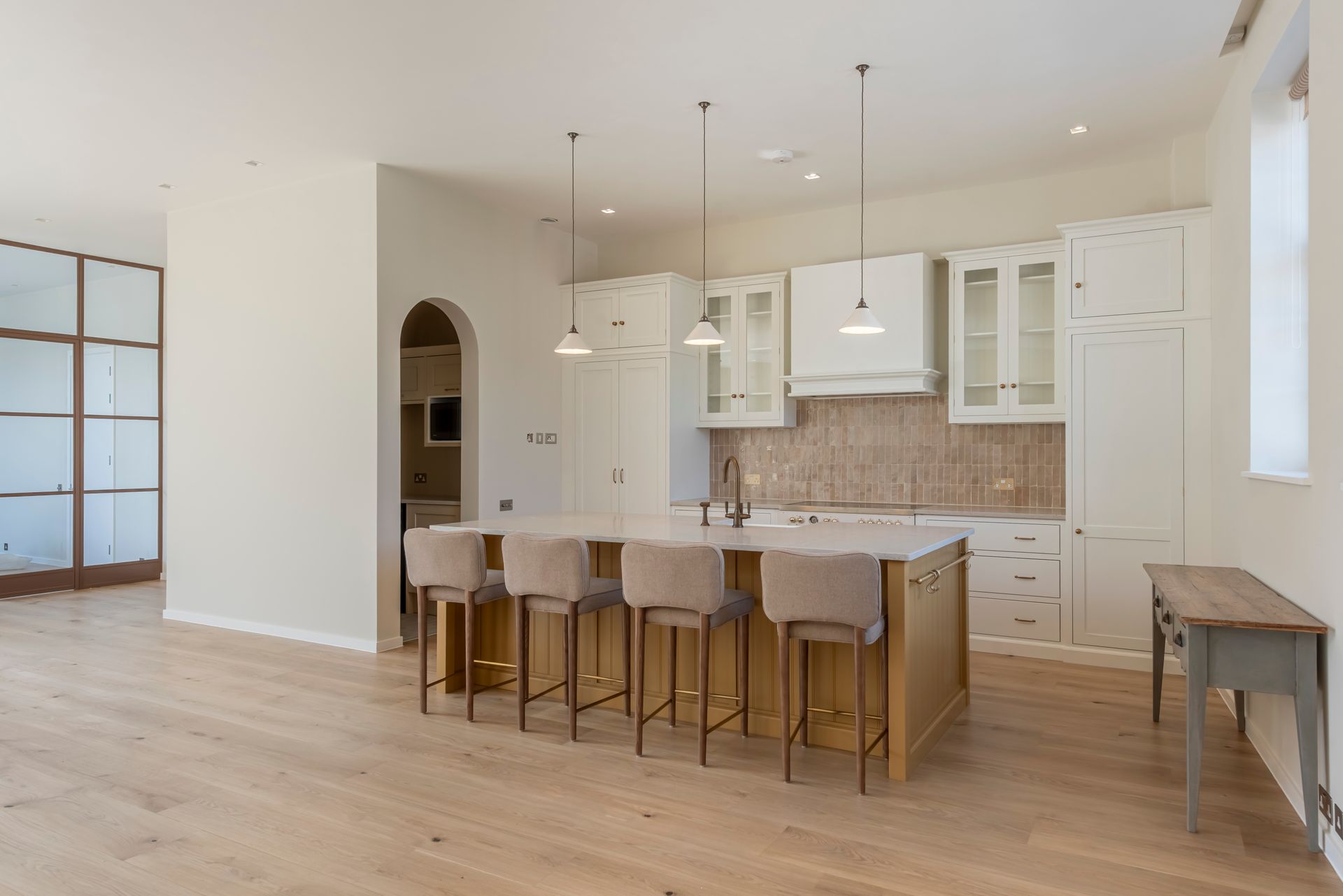 Modern white kitchen with wood island, bar stools, and light wood floors in an open living space