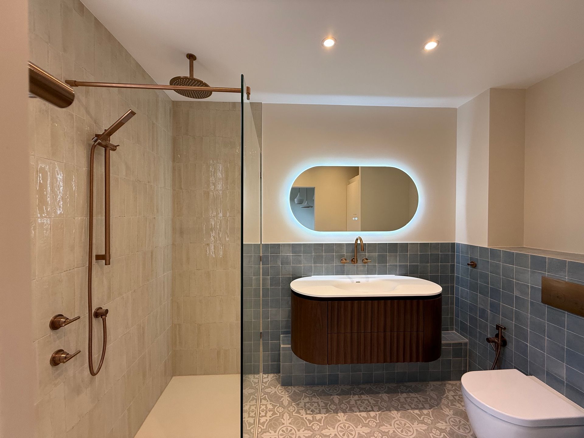 Luxury contemporary bathroom and ensuite featuring a fluted vanity, illuminated mirror, and walk-in shower