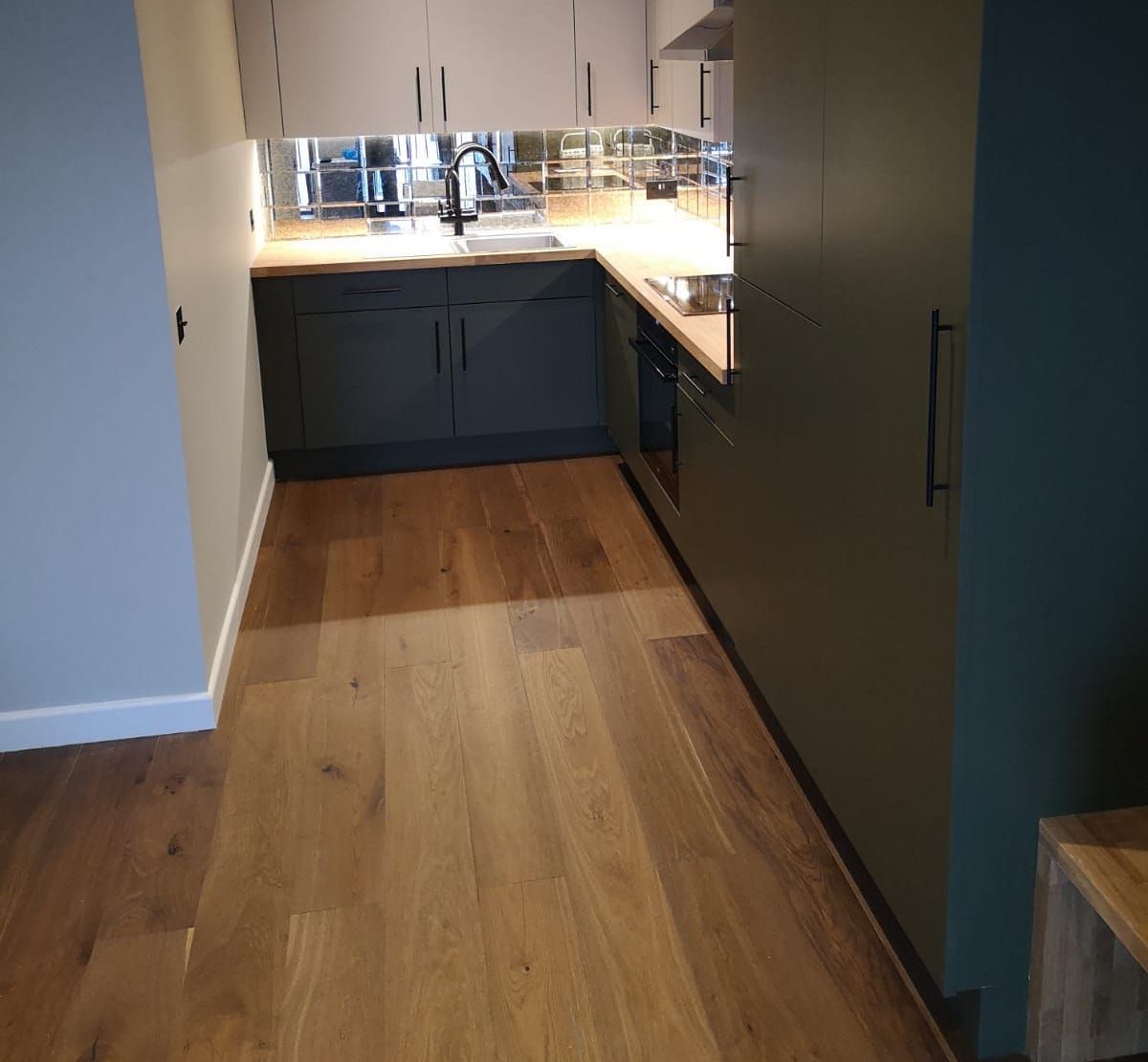Contemporary kitchen with sleek dark cabinetry and warm wood flooring