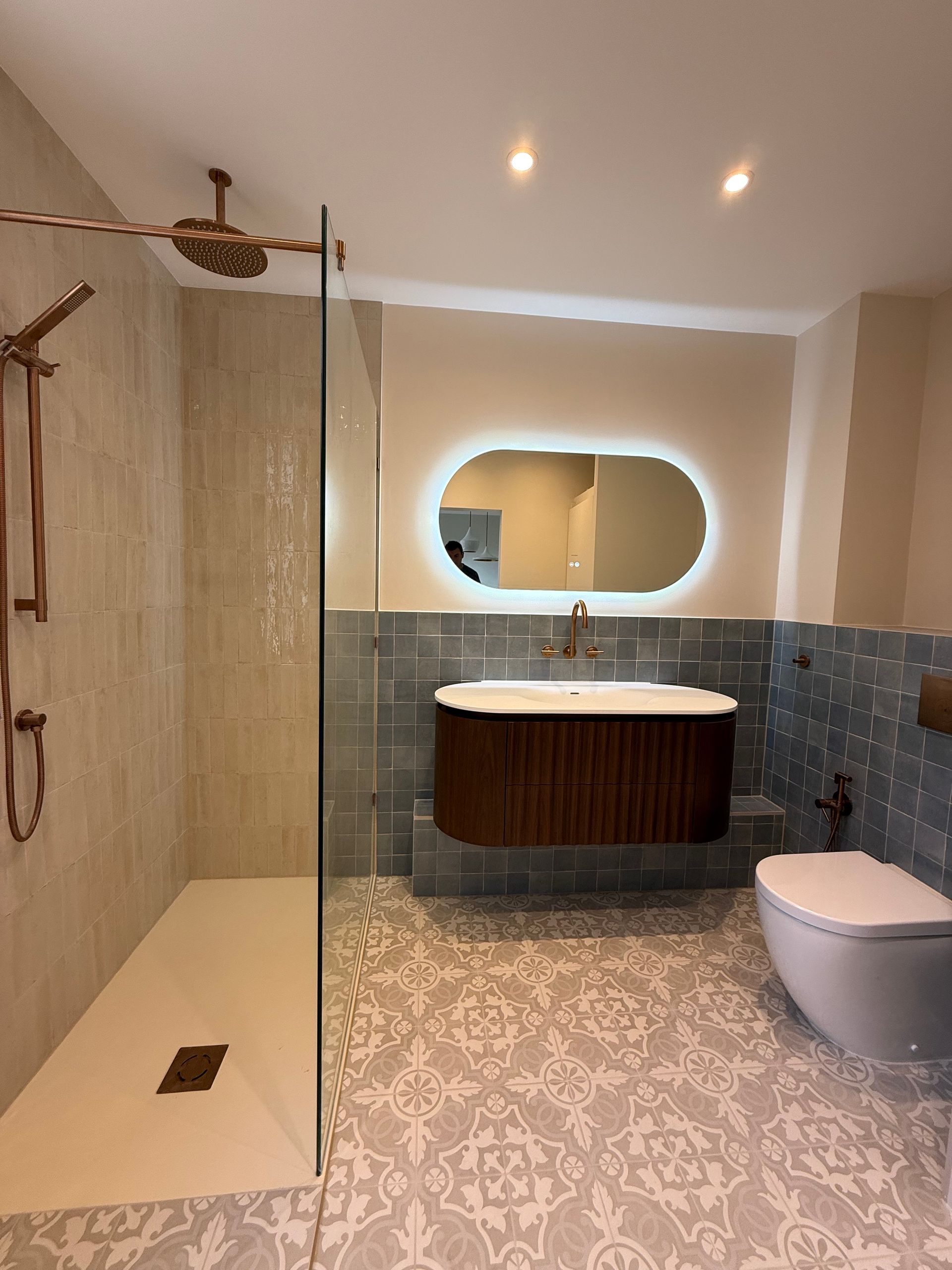 Luxury contemporary bathroom and ensuite featuring a fluted vanity, illuminated mirror, and walk-in shower