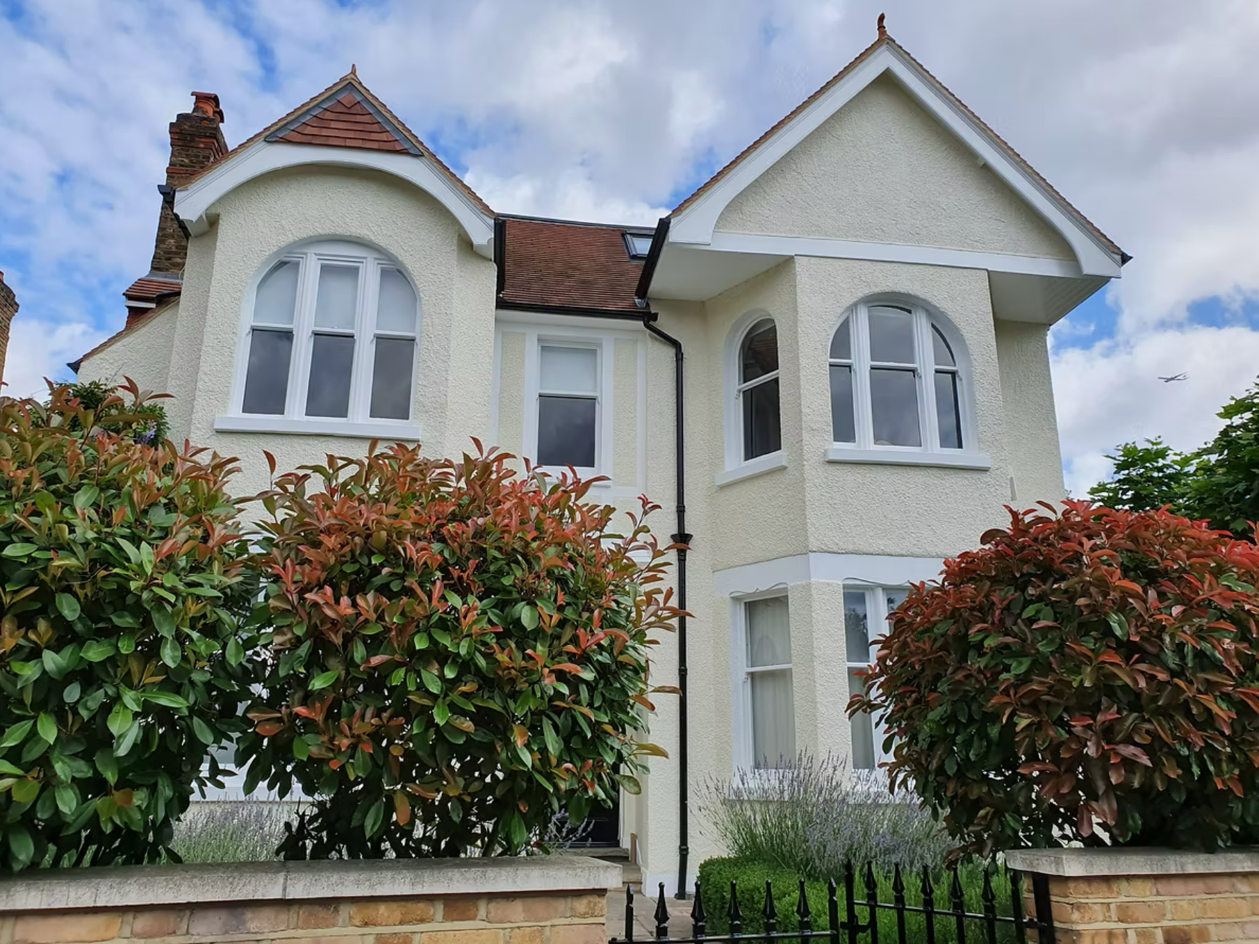 Exterior front view of a completed residential house with rendered walls and arched windows in London