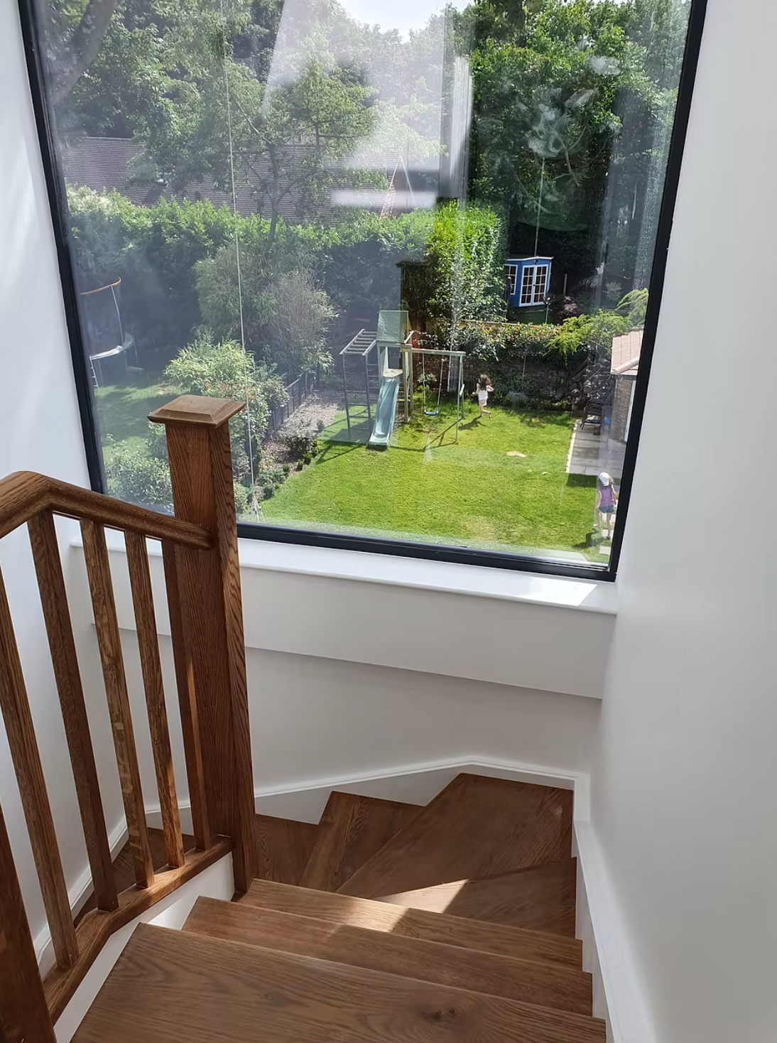 High-angle view looking down out of a window toward a green residential garden and play equipment in London