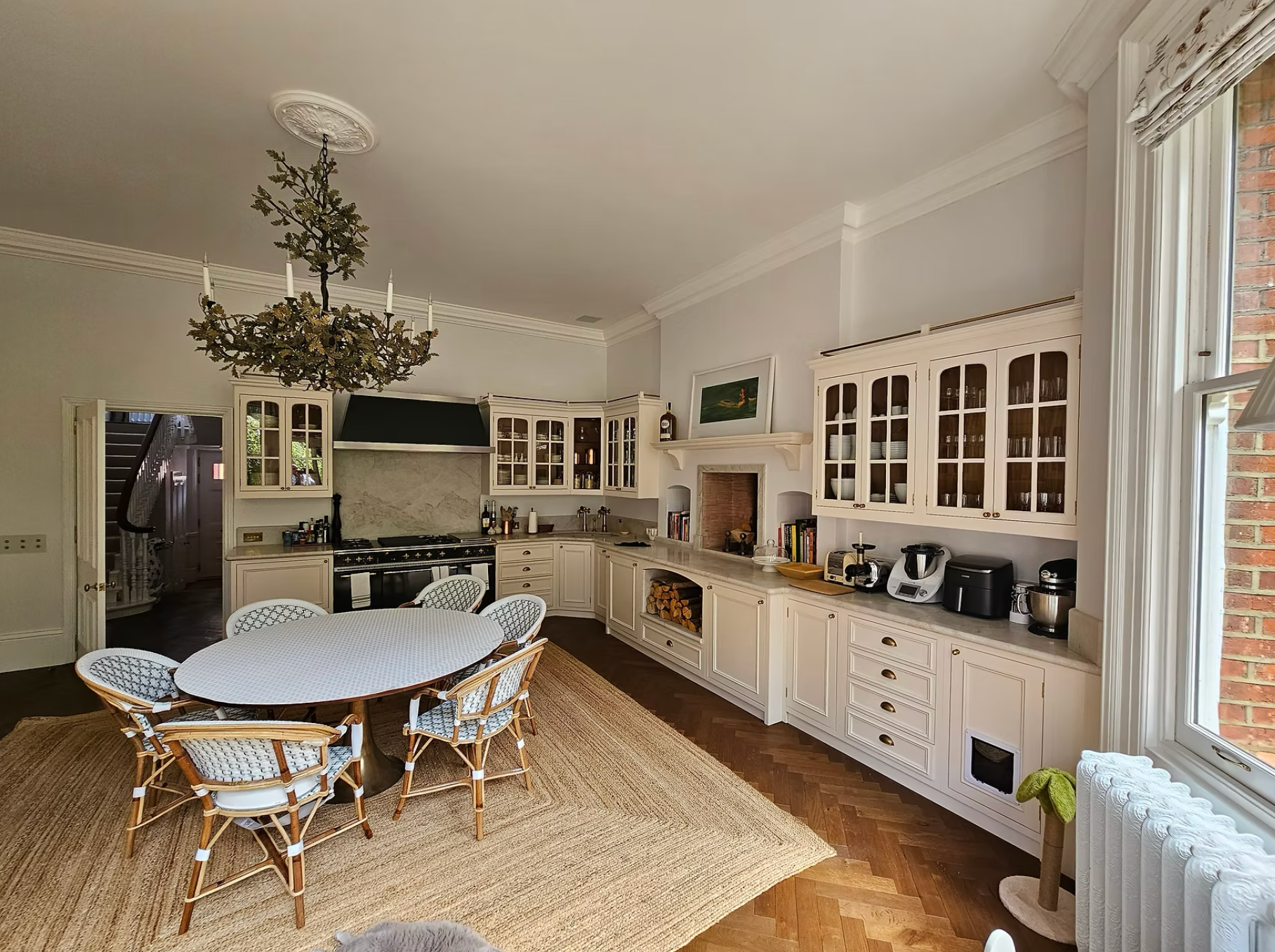 Spacious traditional kitchen and dining area featuring classic white cabinetry, large windows, and a chandelier