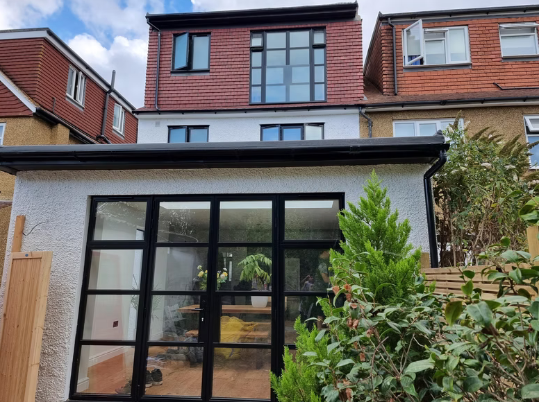 Modern rear house extension with large black framed bi-fold glass doors and patio area