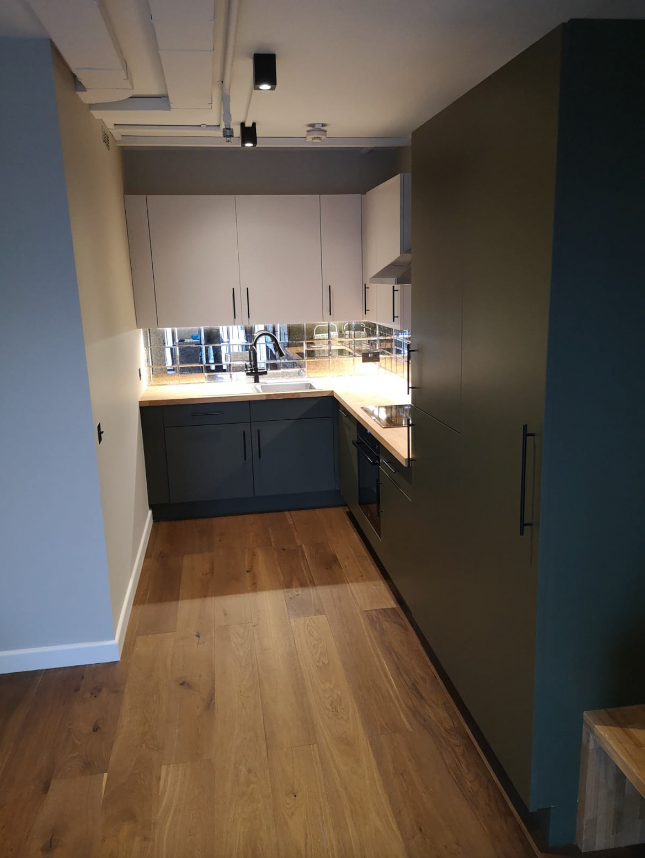 Modern kitchen with sleek dark cabinetry and mirrored splashback