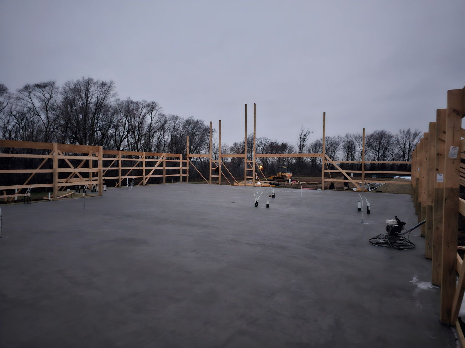Concrete slab with wooden framing for a building under construction, exterior view. Gray concrete, wooden structure, overcast sky.
