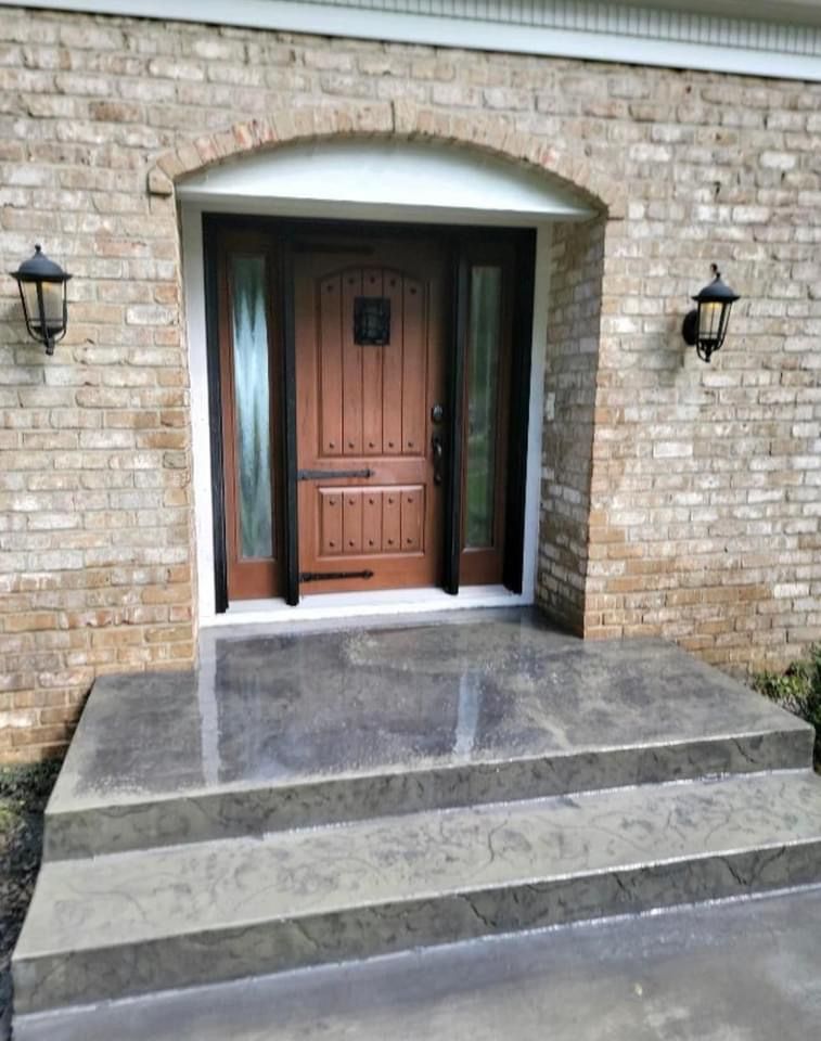 Brown wooden door with side glass panels and brick facade entrance. Two steps lead to the door.