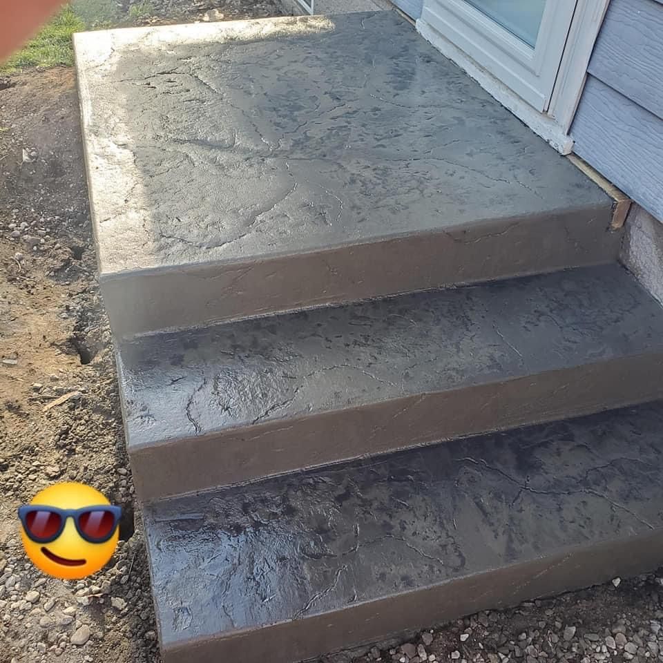 Gray concrete steps leading to a building's entrance. The textured surface is shaded.