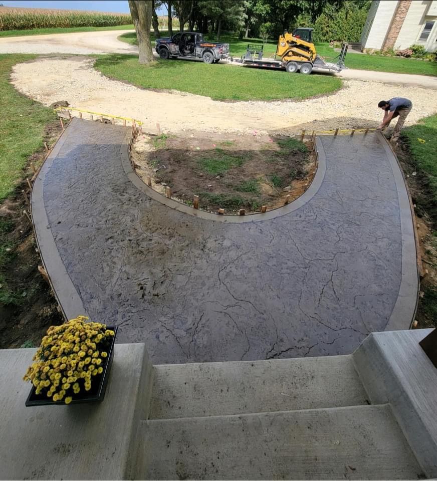 Concrete driveway construction with a worker, steps leading up, and a yellow flower pot.