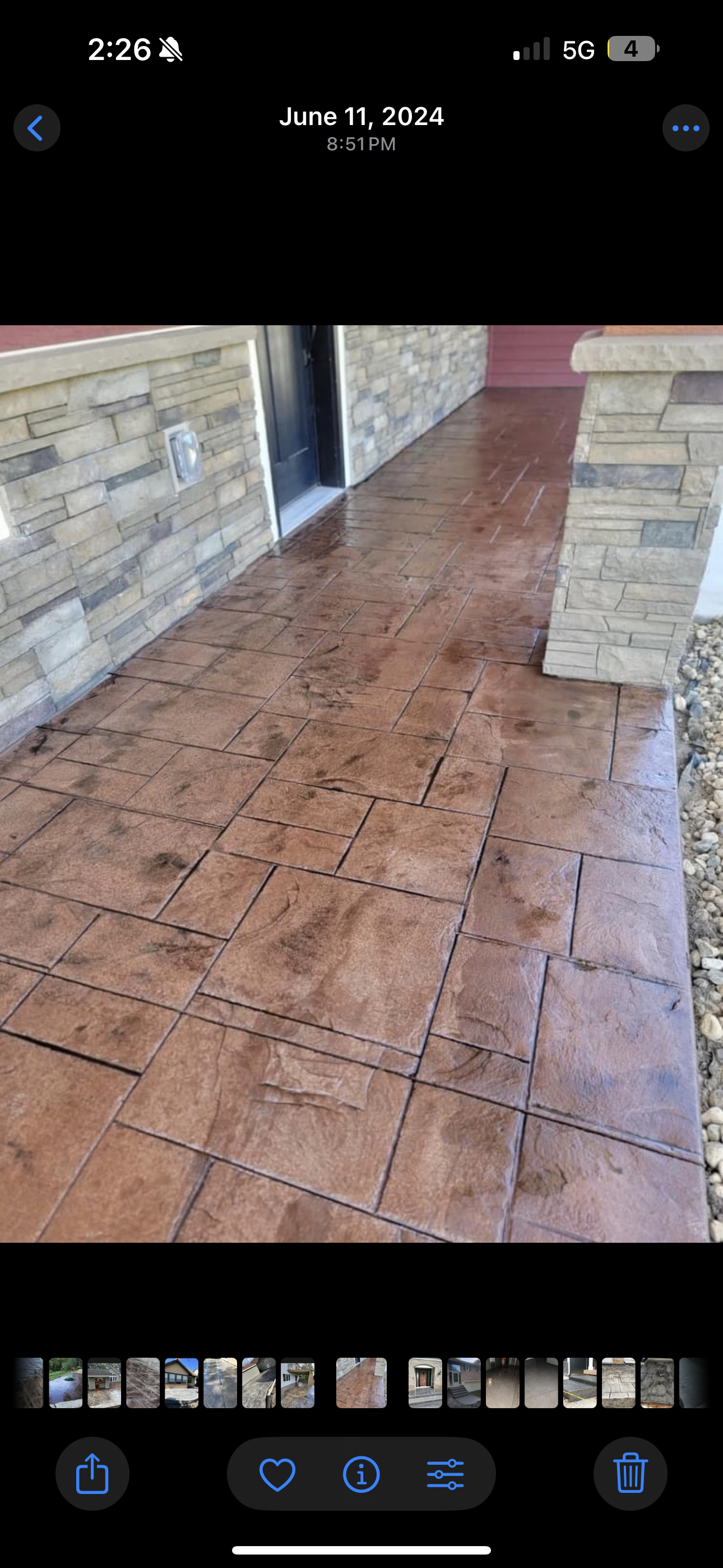 Brown stamped concrete walkway with stone accents and a dark door.