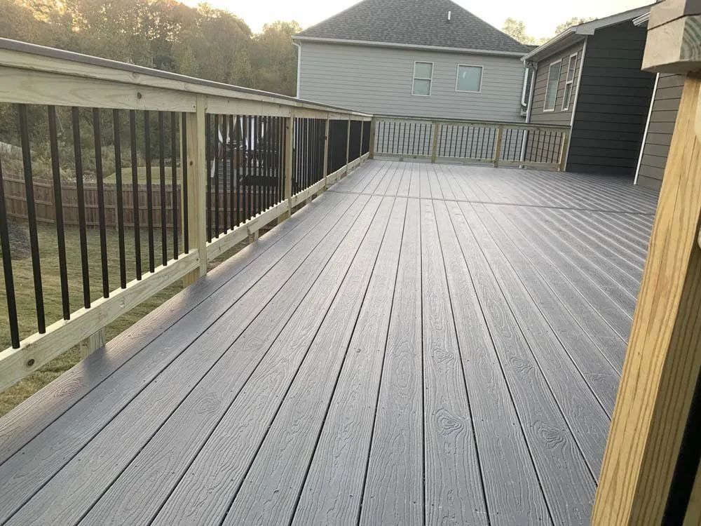 Empty composite deck with railing, overlooking a yard and neighboring houses at sunset