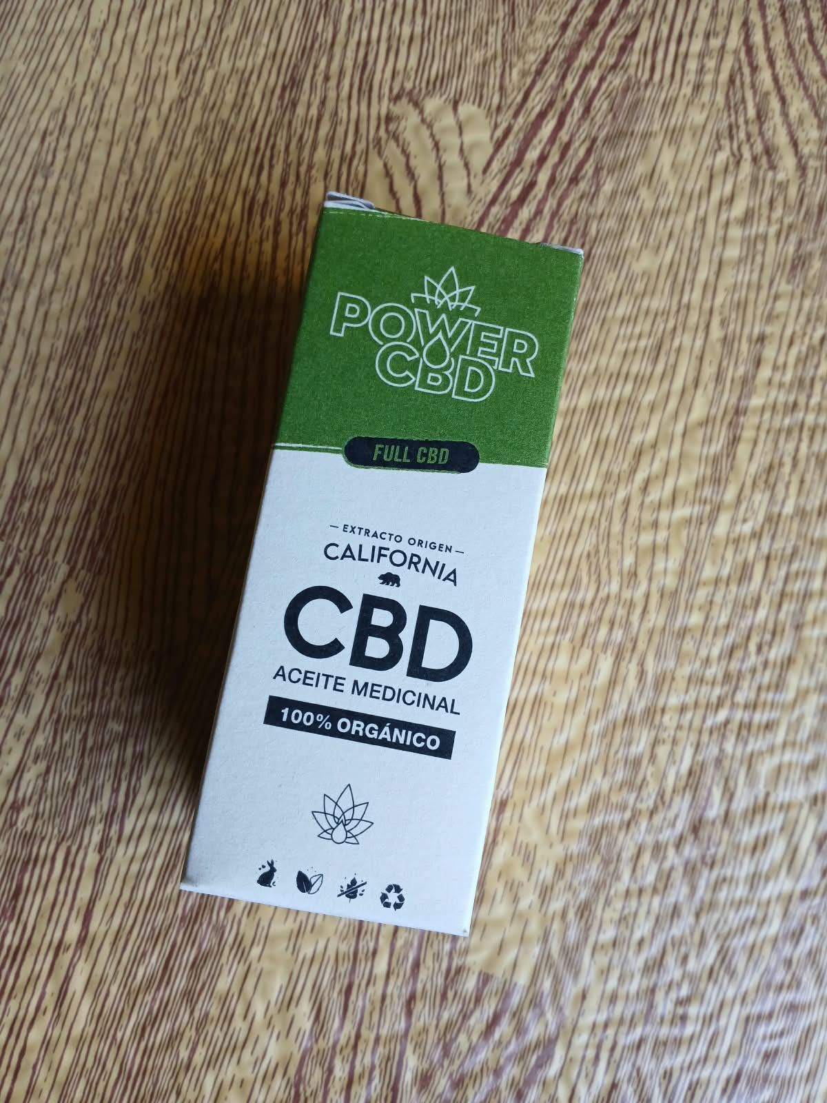 Caja verde y blanca de suplementos Power CBD sobre un suelo de madera, etiquetada como “CBD” y “ACURE NATURAL”.