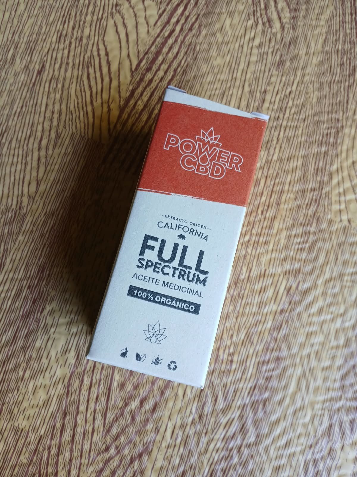 Caja de cartuchos de cannabis de espectro completo de color naranja y blanco sobre una superficie de madera.
