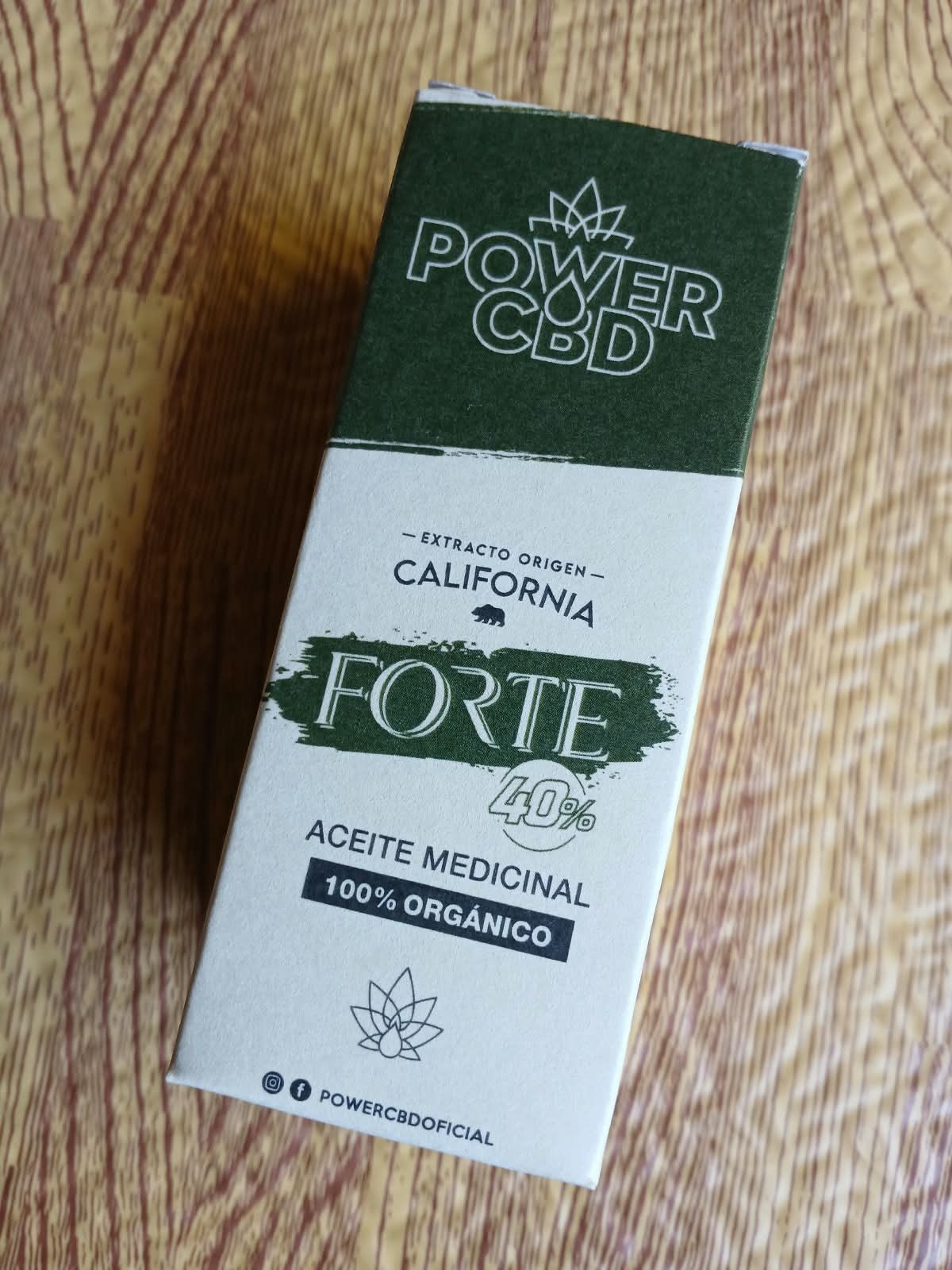 Caja de aceite medicinal Power CBD Forte de color verde y blanco sobre una superficie de madera.