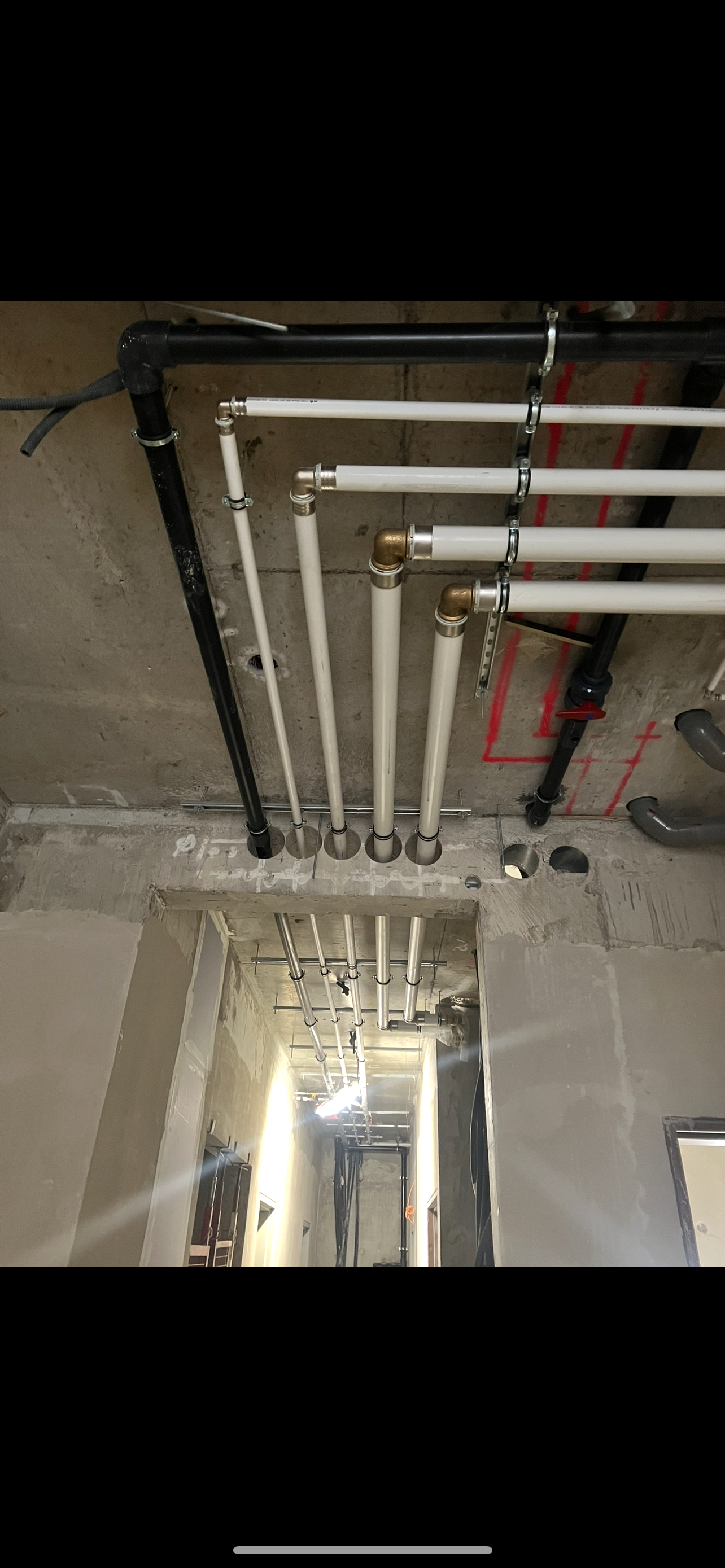 Tuyaux et conduits apparents au plafond au-dessus d'une ouverture dans l'intérieur d'un chantier de construction