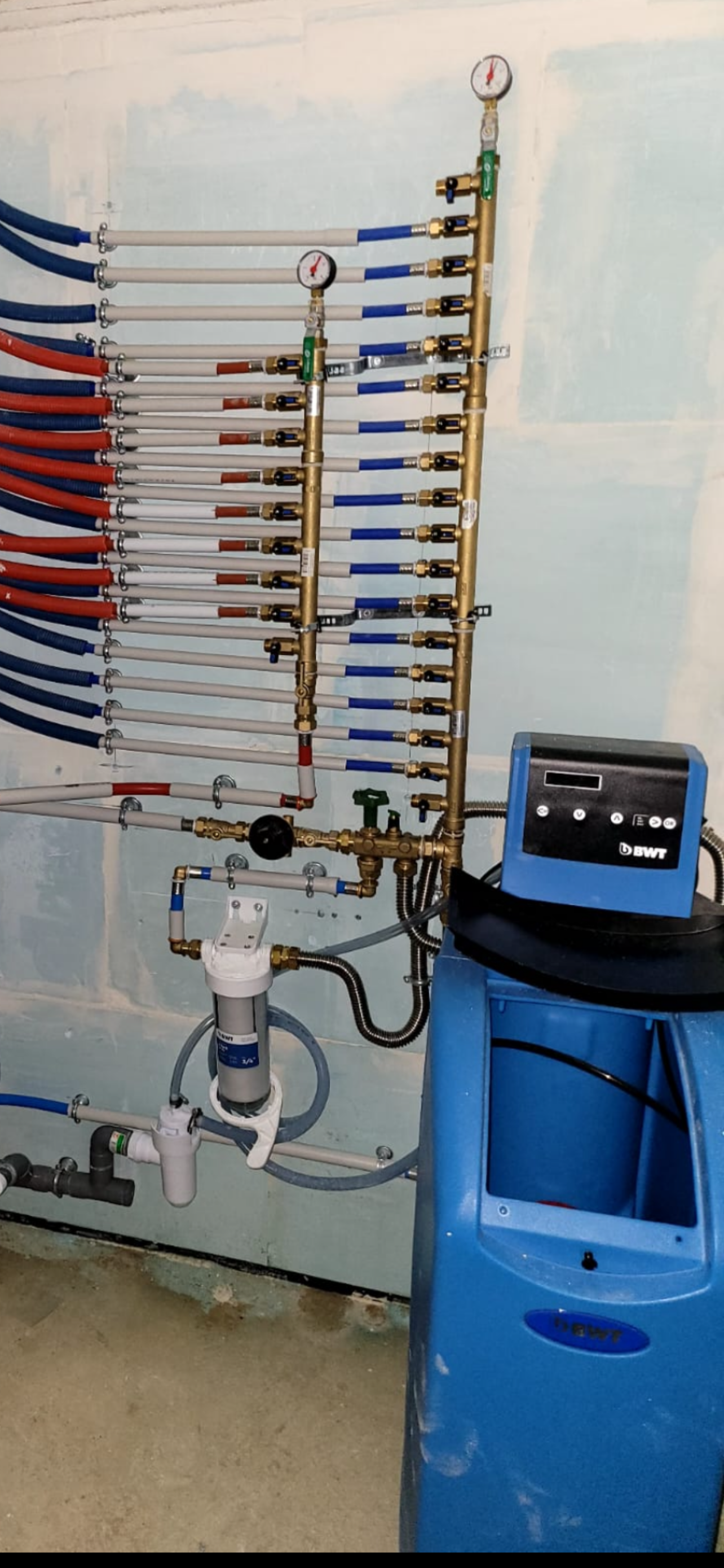 Collecteur mural de tuyaux de gaz médicaux à côté d'un chariot d'équipement bleu dans une salle clinique