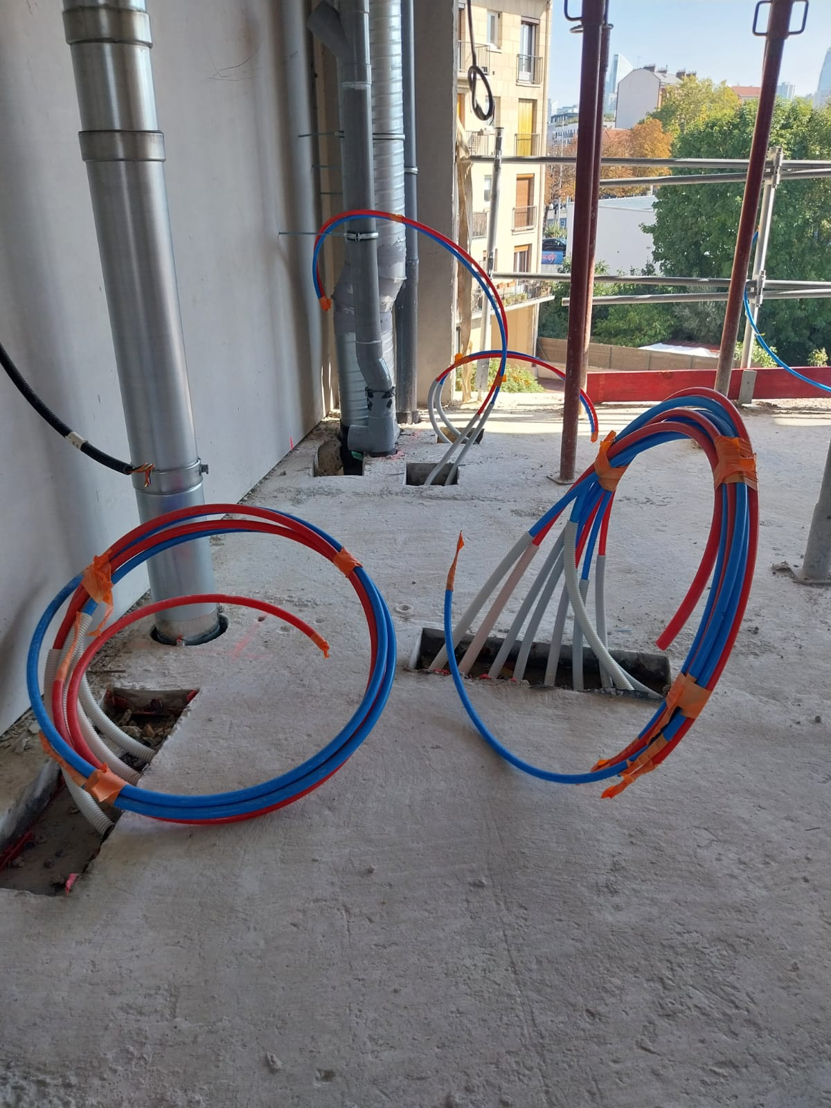 Chantier de construction avec des câbles rouges et bleus enroulés sur un sol 