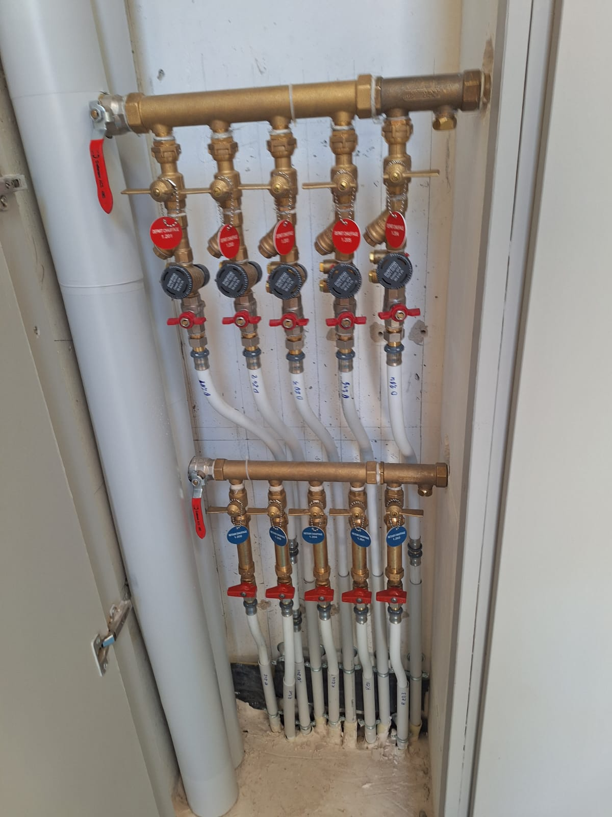 Collecteur de tuyaux d'eau chaude et froide avec vannes d'arrêt rouges et bleues dans une armoire utilitaire