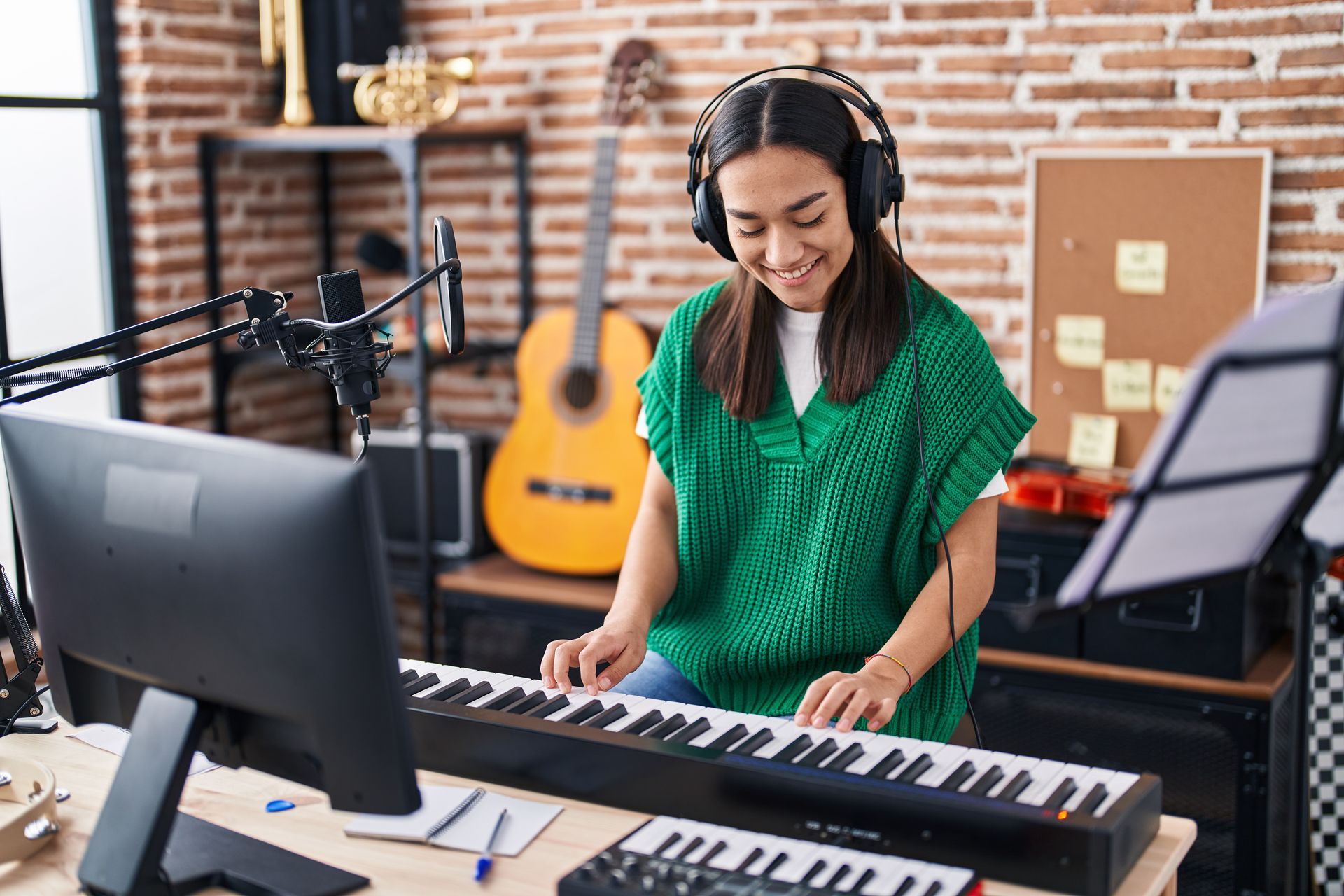 Musician in green shirt playing keyboard and singing into a microphone in a home studio