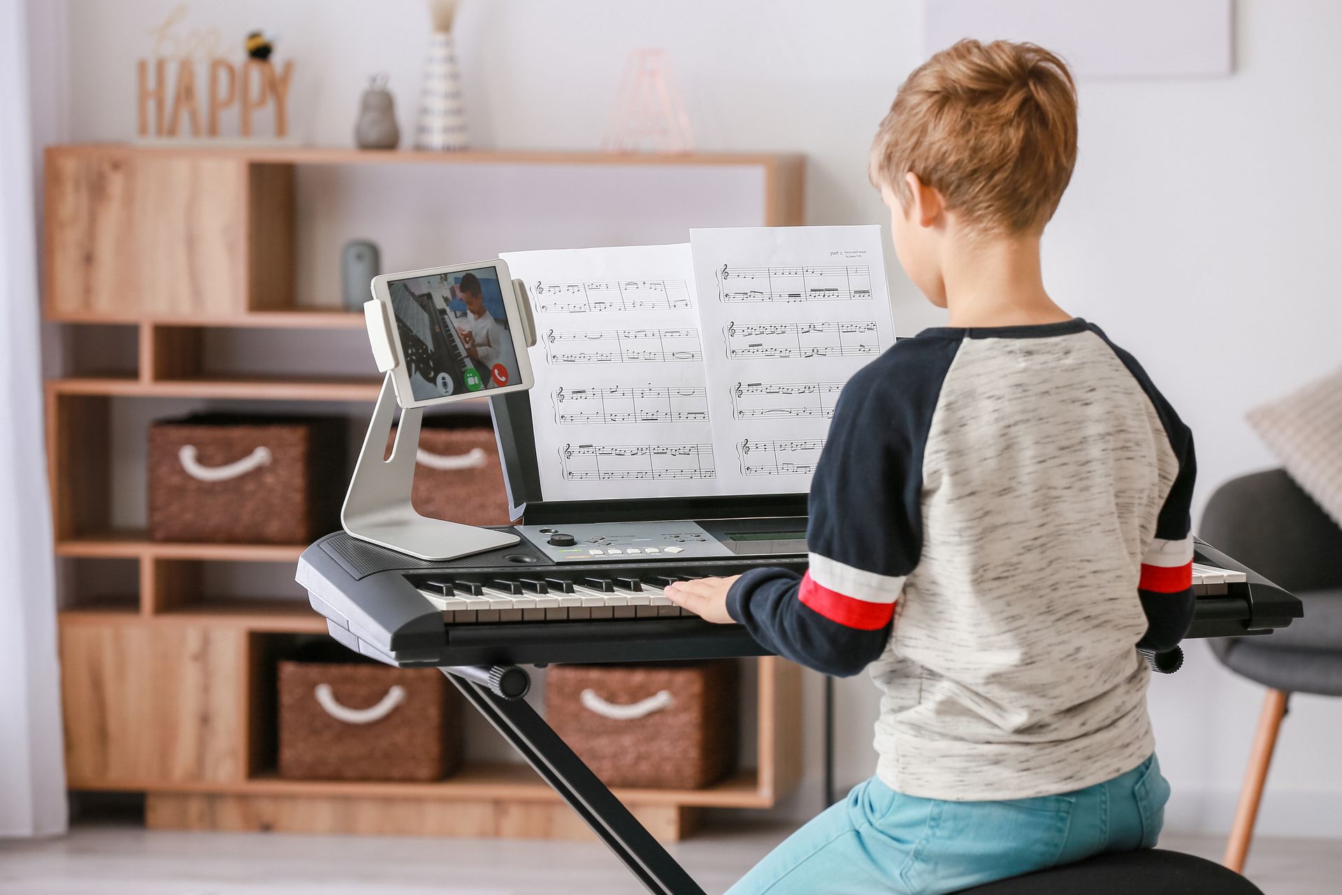 Child seated at a keyboard with sheet music in a bright living room