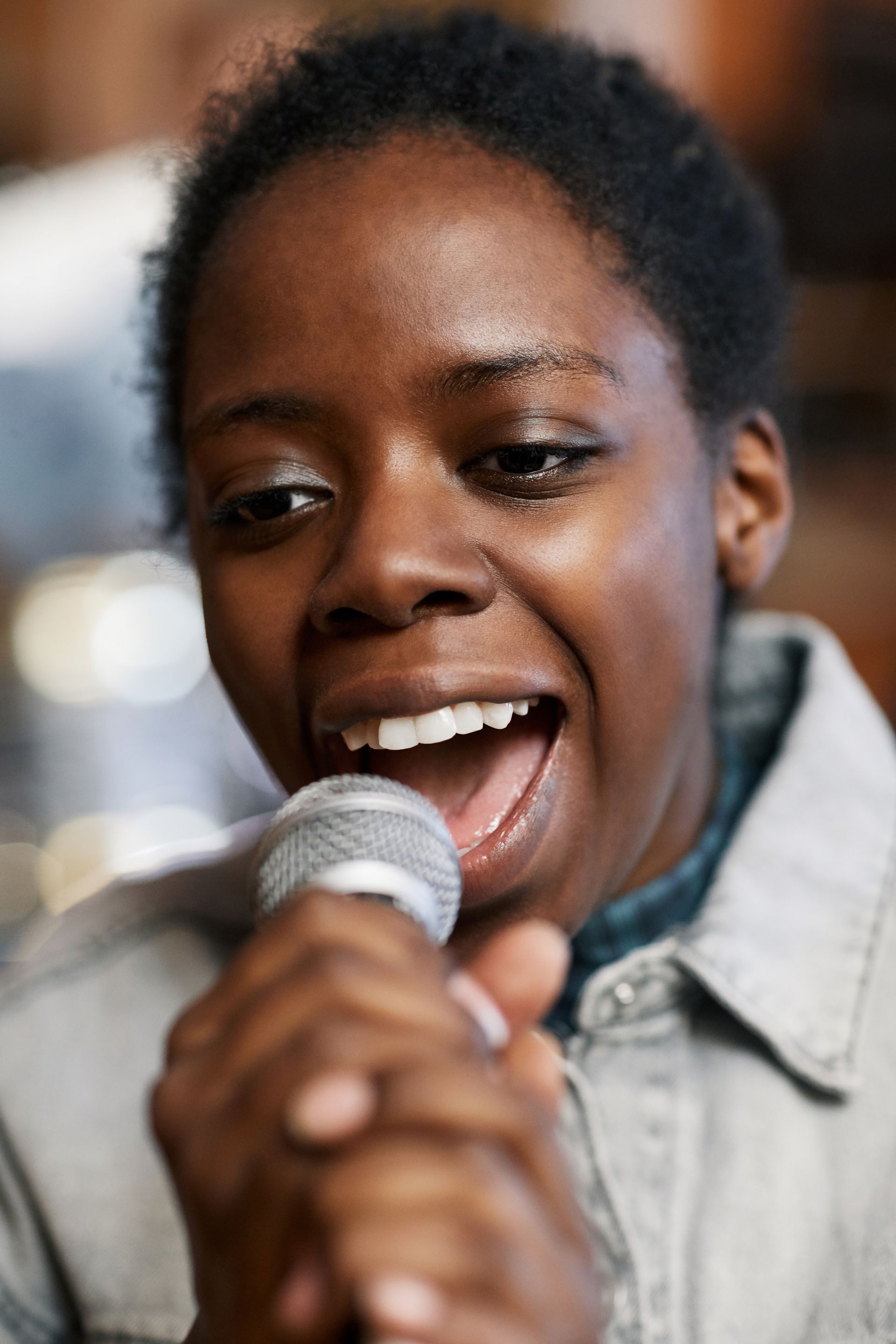 A woman singing into a microphone with her mouth open