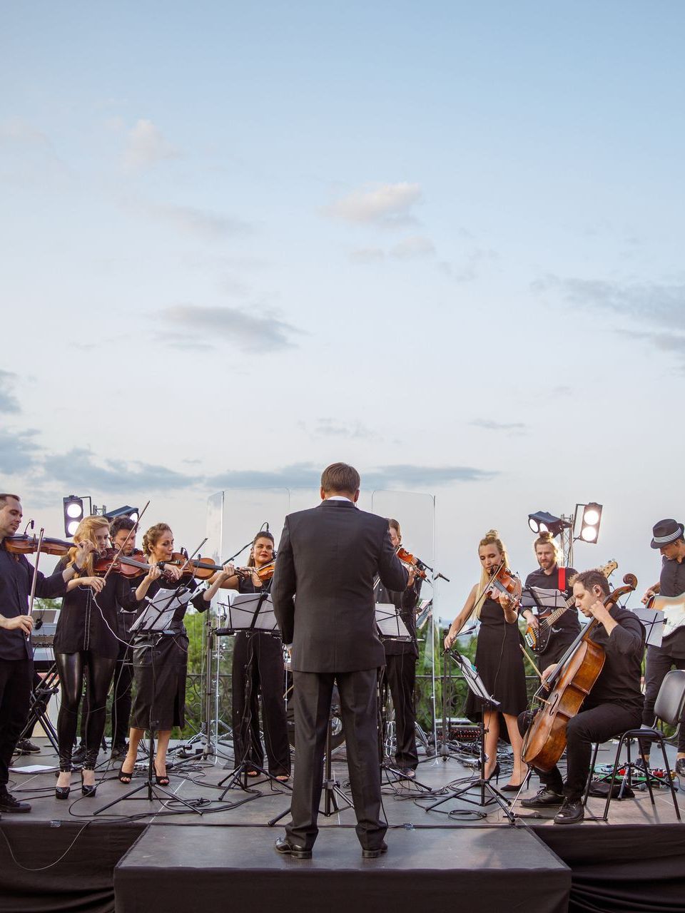 A man in a suit is leading an orchestra on a stage.