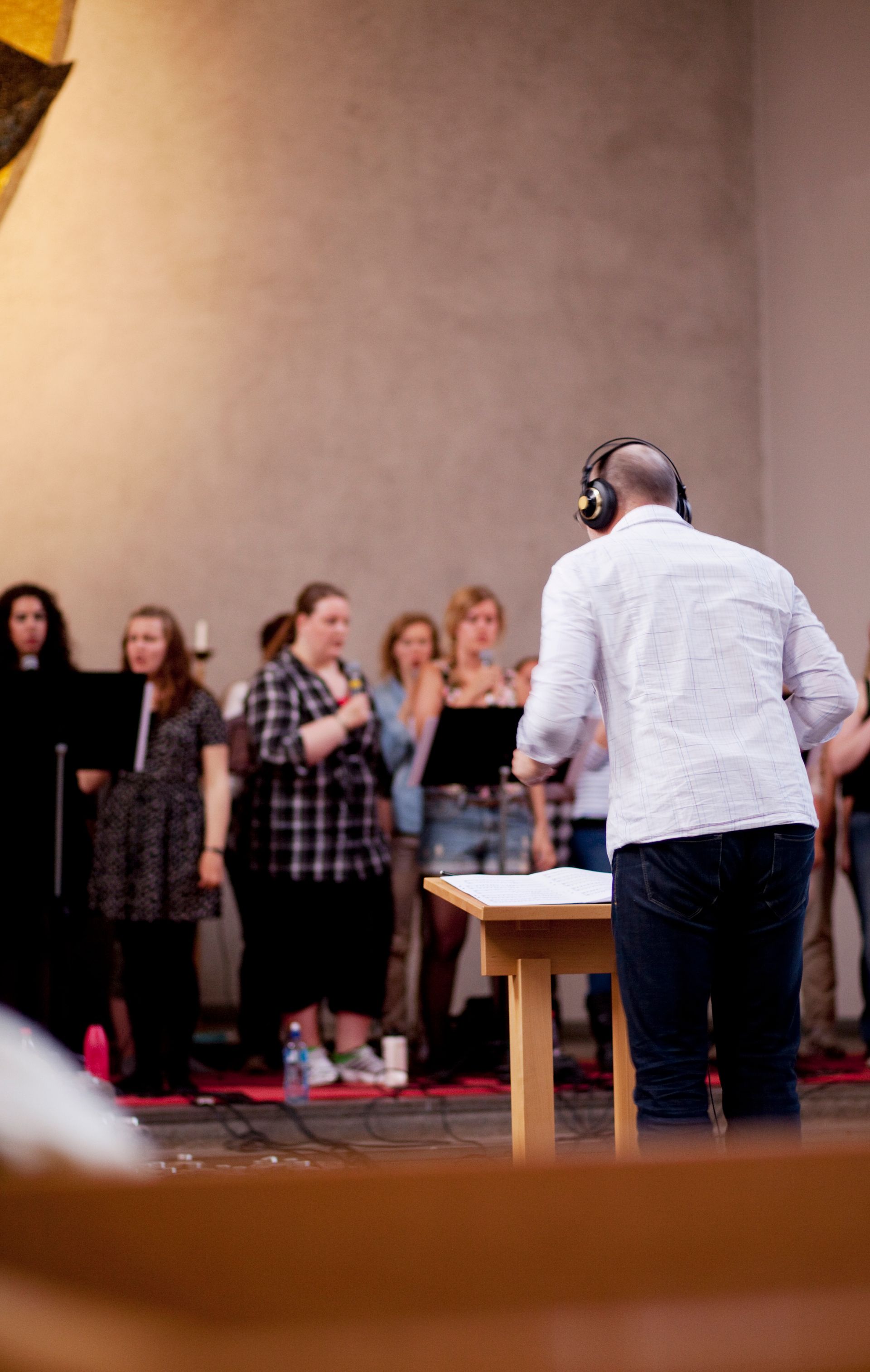 A man wearing headphones is standing in front of a group of people.