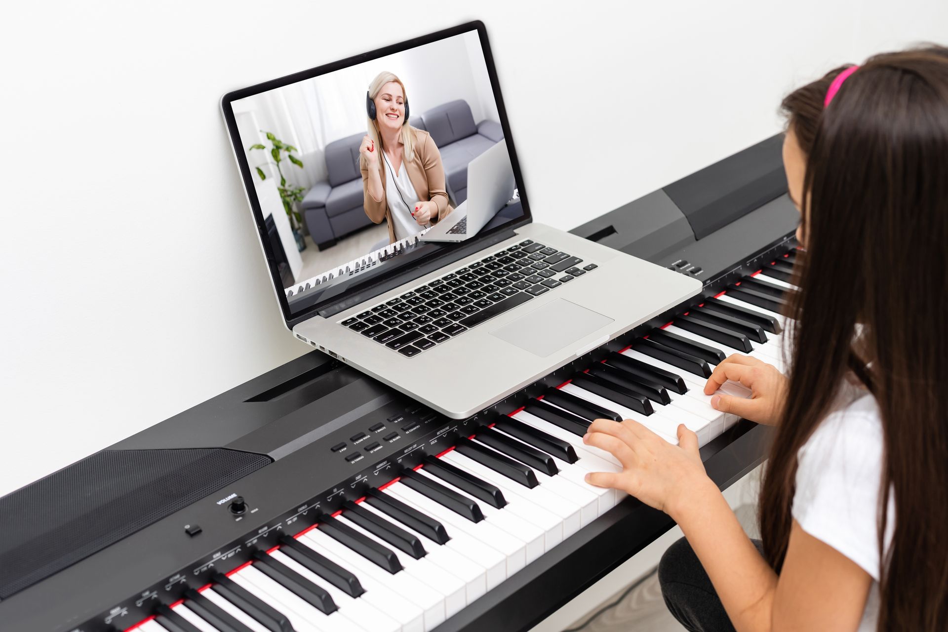 Woman plays digital piano while video chatting on a laptop screen