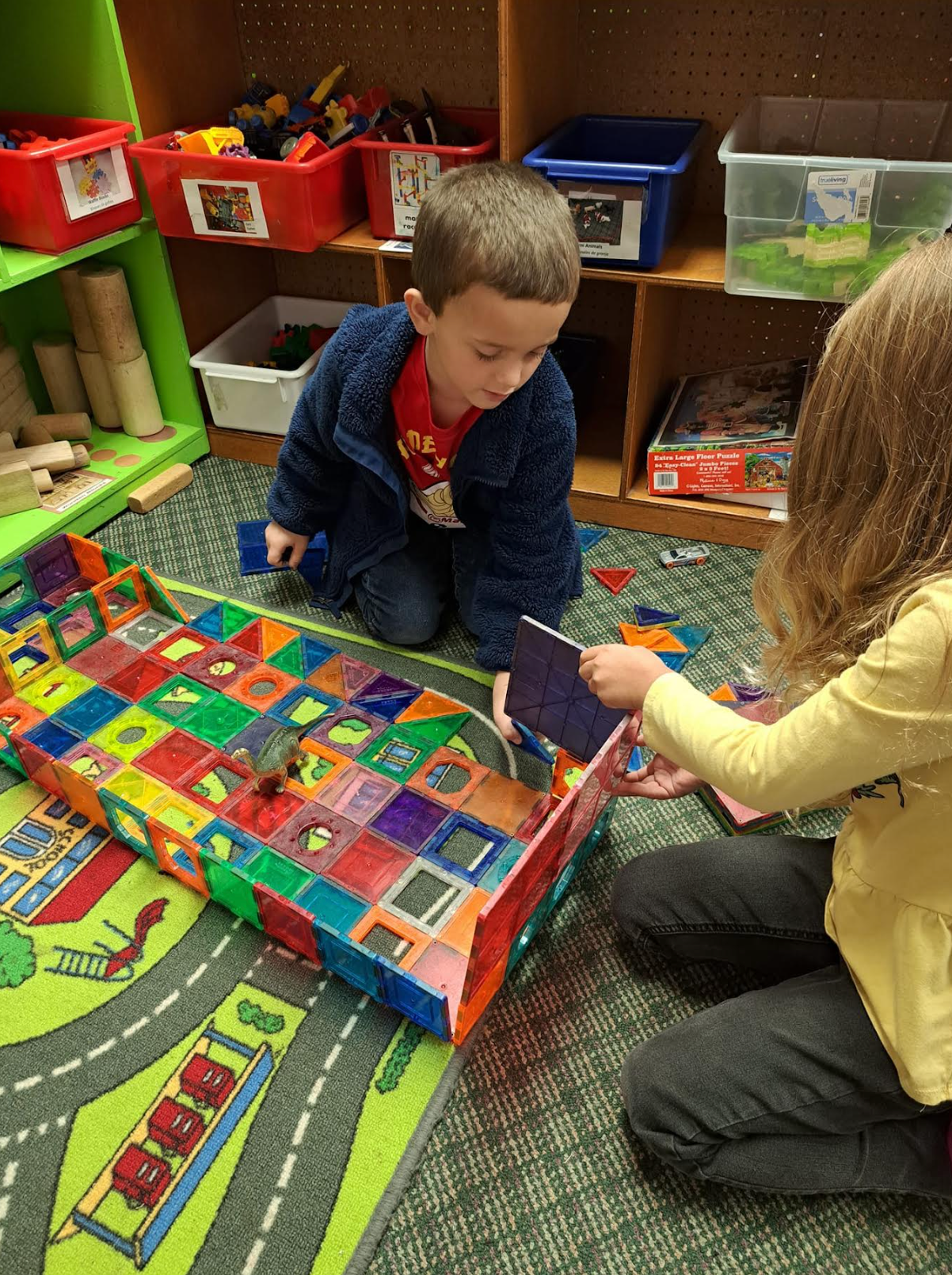 A boy and a girl are playing with toys in a room.