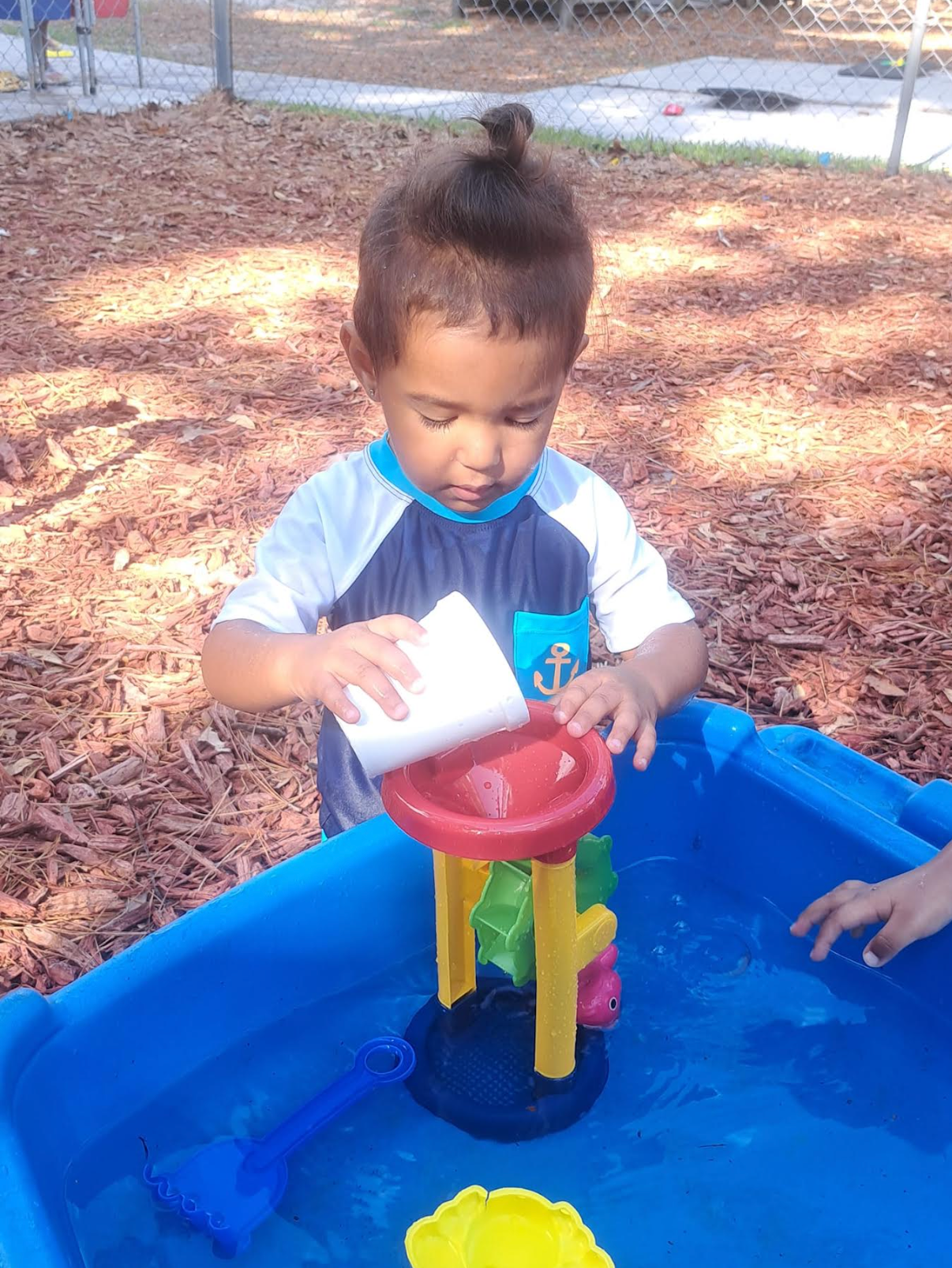 A little boy is playing in a water table