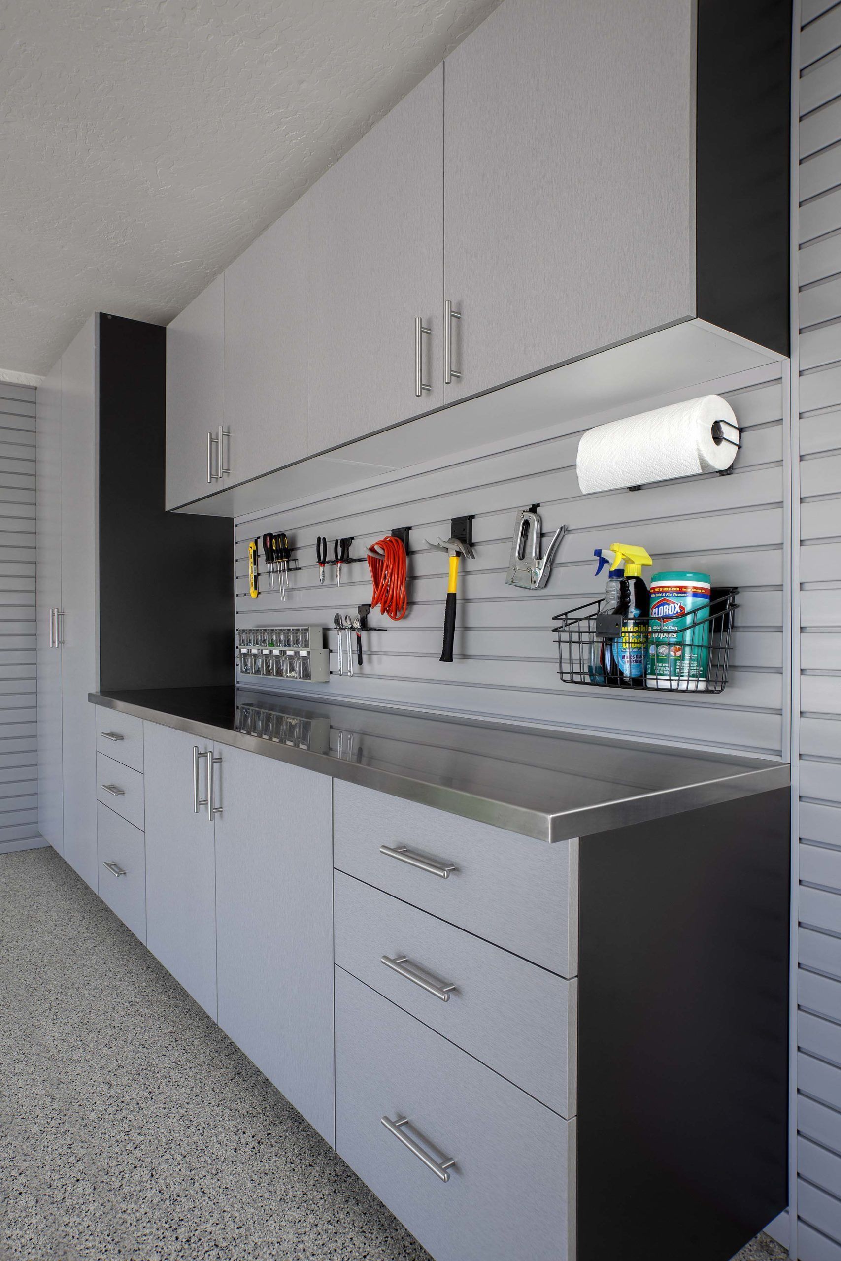 a workbench with wooden cabinets , a paper towel holder , and a hose hanging on the wall .