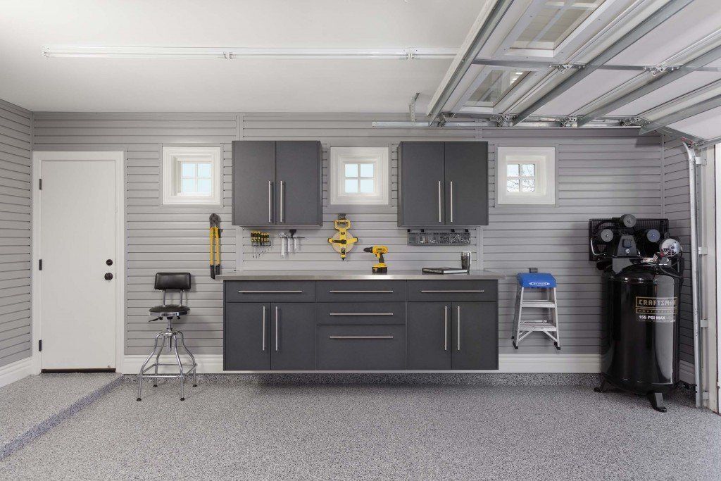 A garage with gray wall cabinets and a workbench.