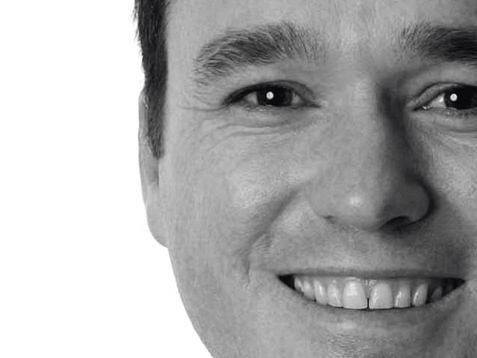 A close up of a man 's face smiling in a black and white photo.