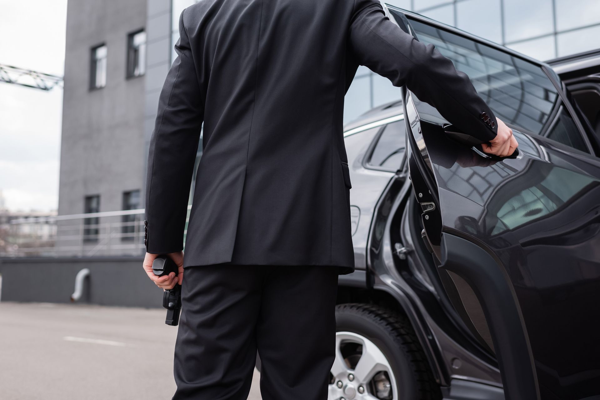 A man in a suit is opening the door of a car.
